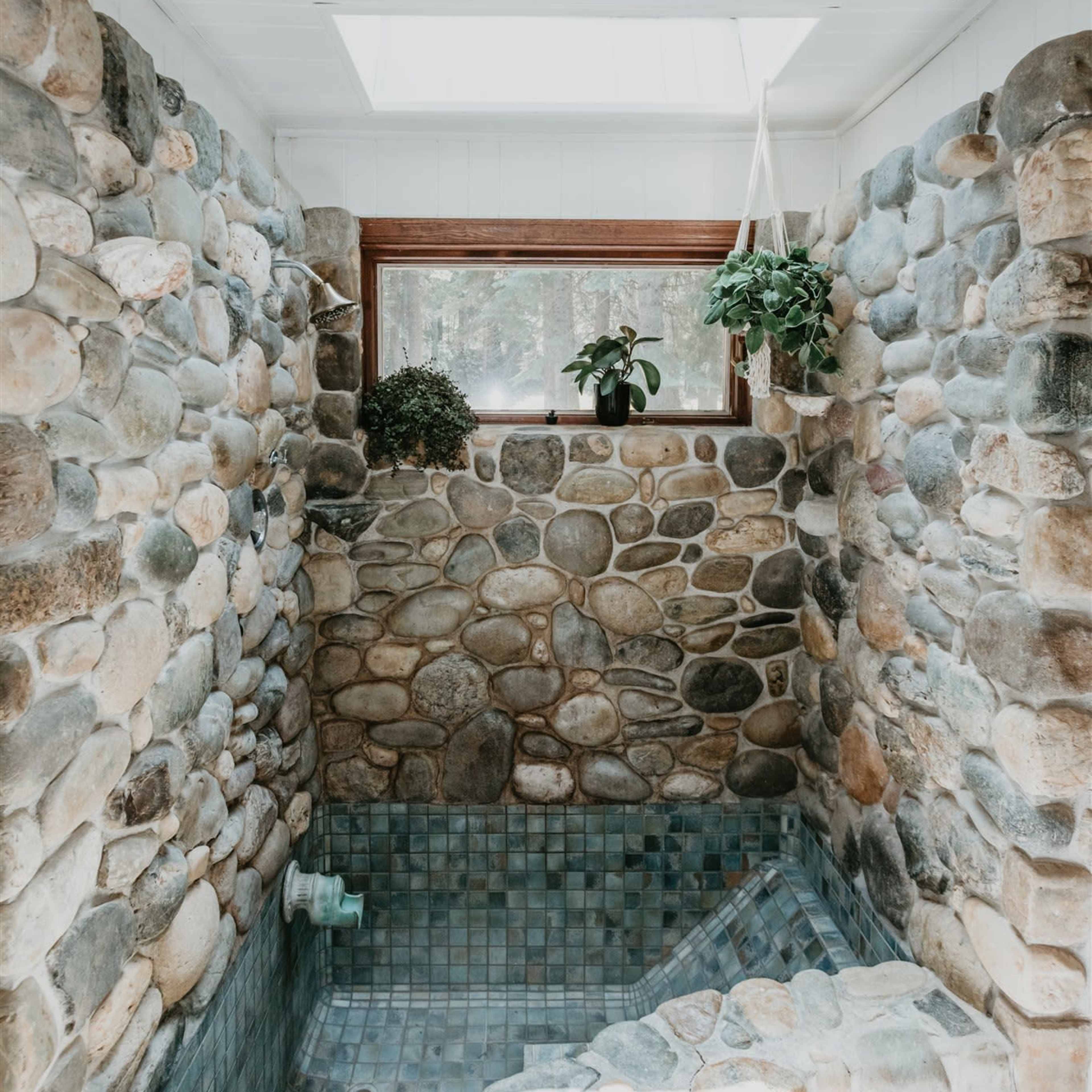 A stone-walled shower space with a small built-in bench and a skylight above.