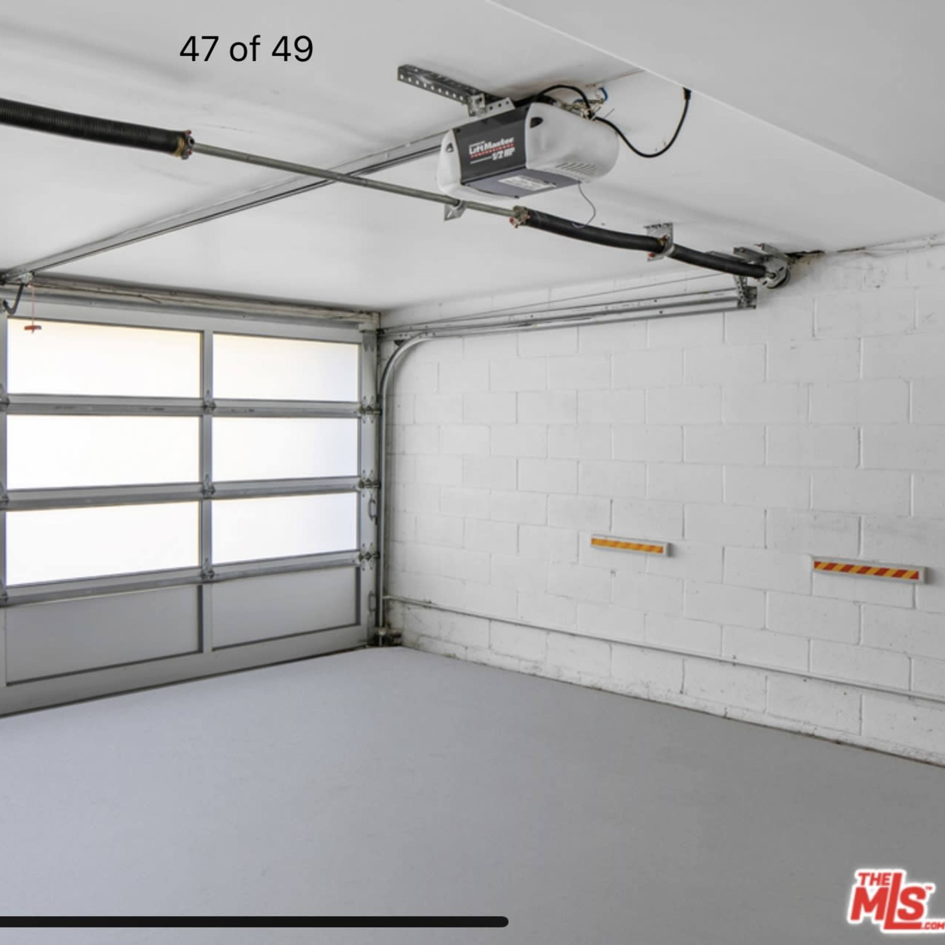 An empty garage with a large door that features multiple windows and a smooth, gray floor.