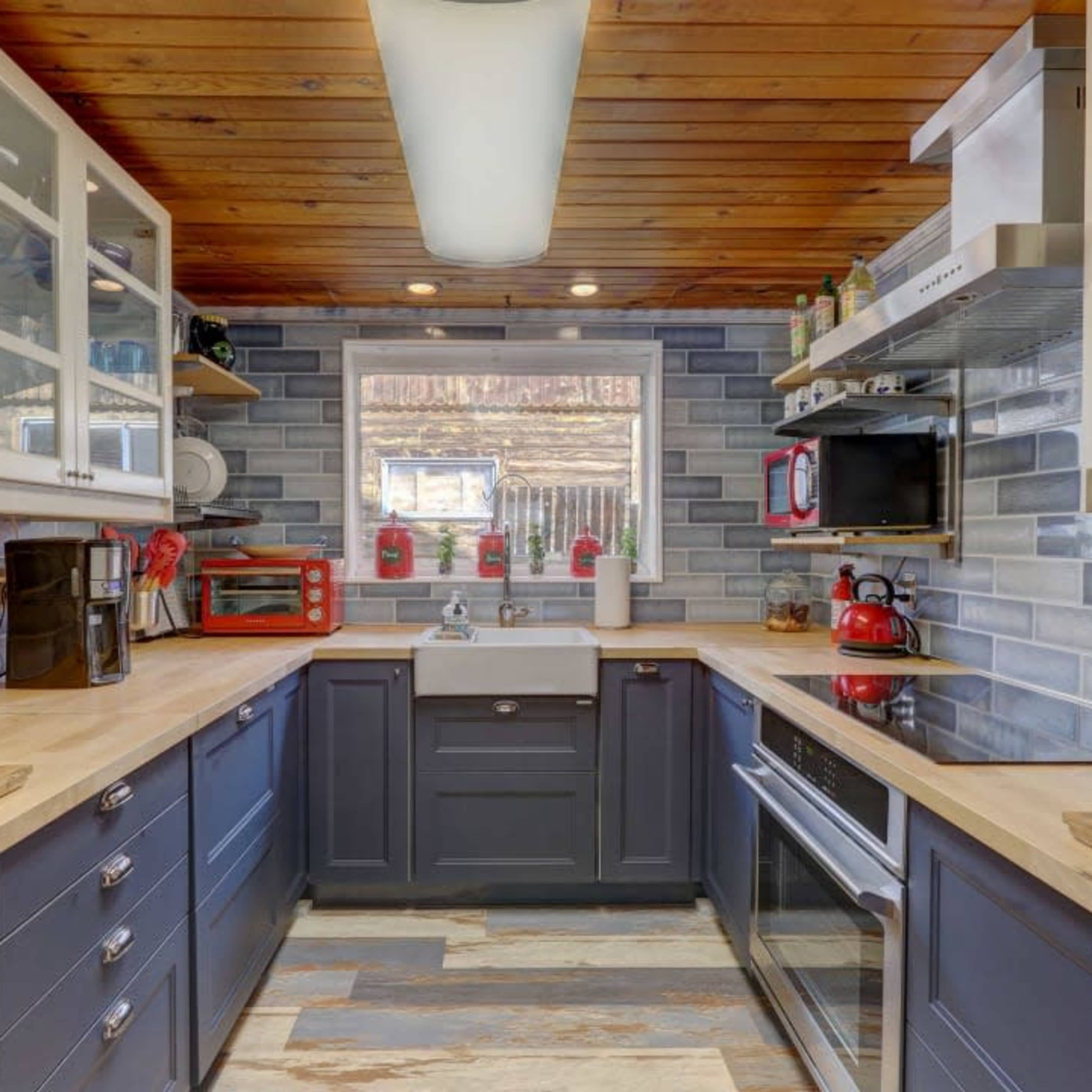 The kitchen features dark blue cabinetry, wooden countertops, and gray tiled walls with a window providing natural light.