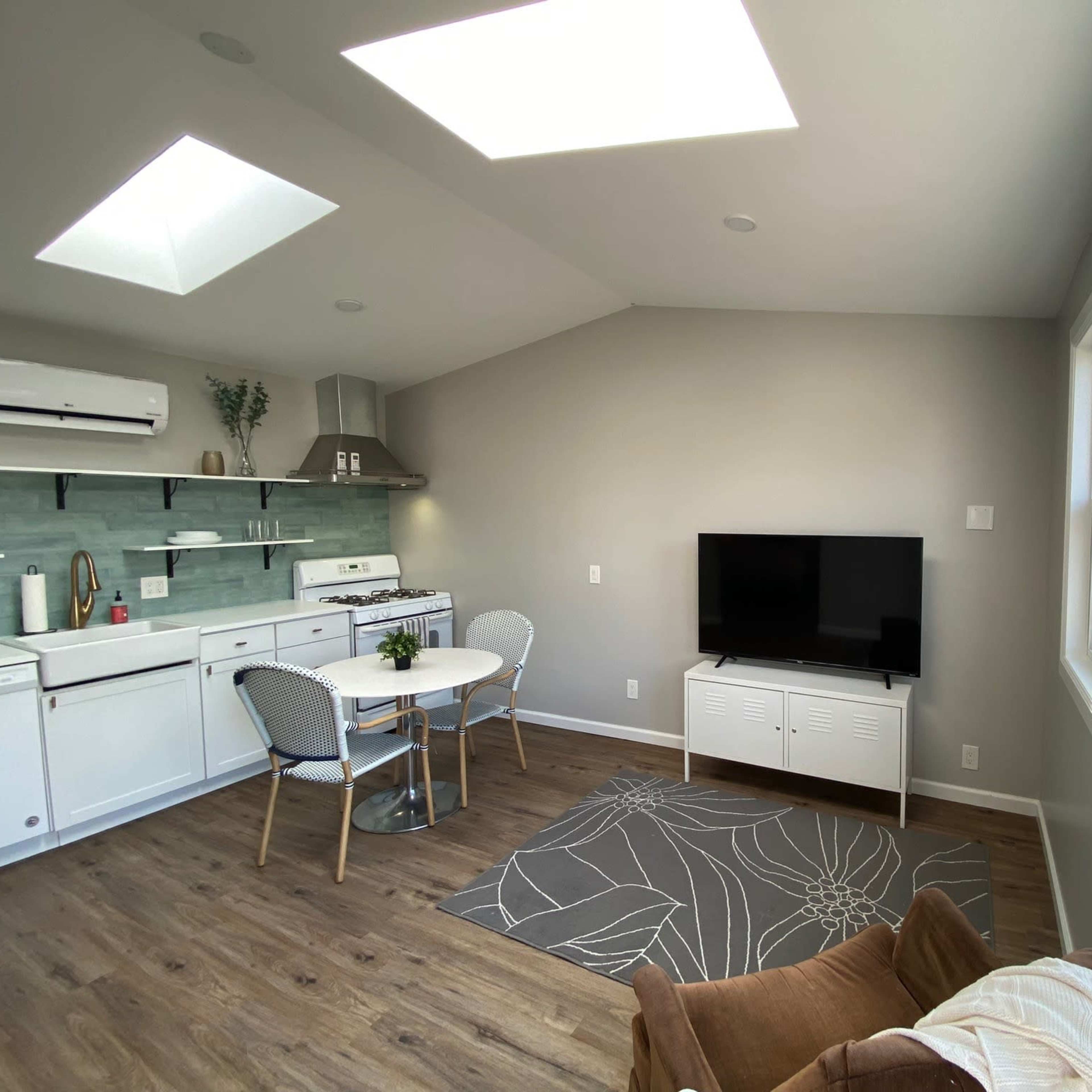 A modern, open-concept living area with a kitchen, dining table, and a television.