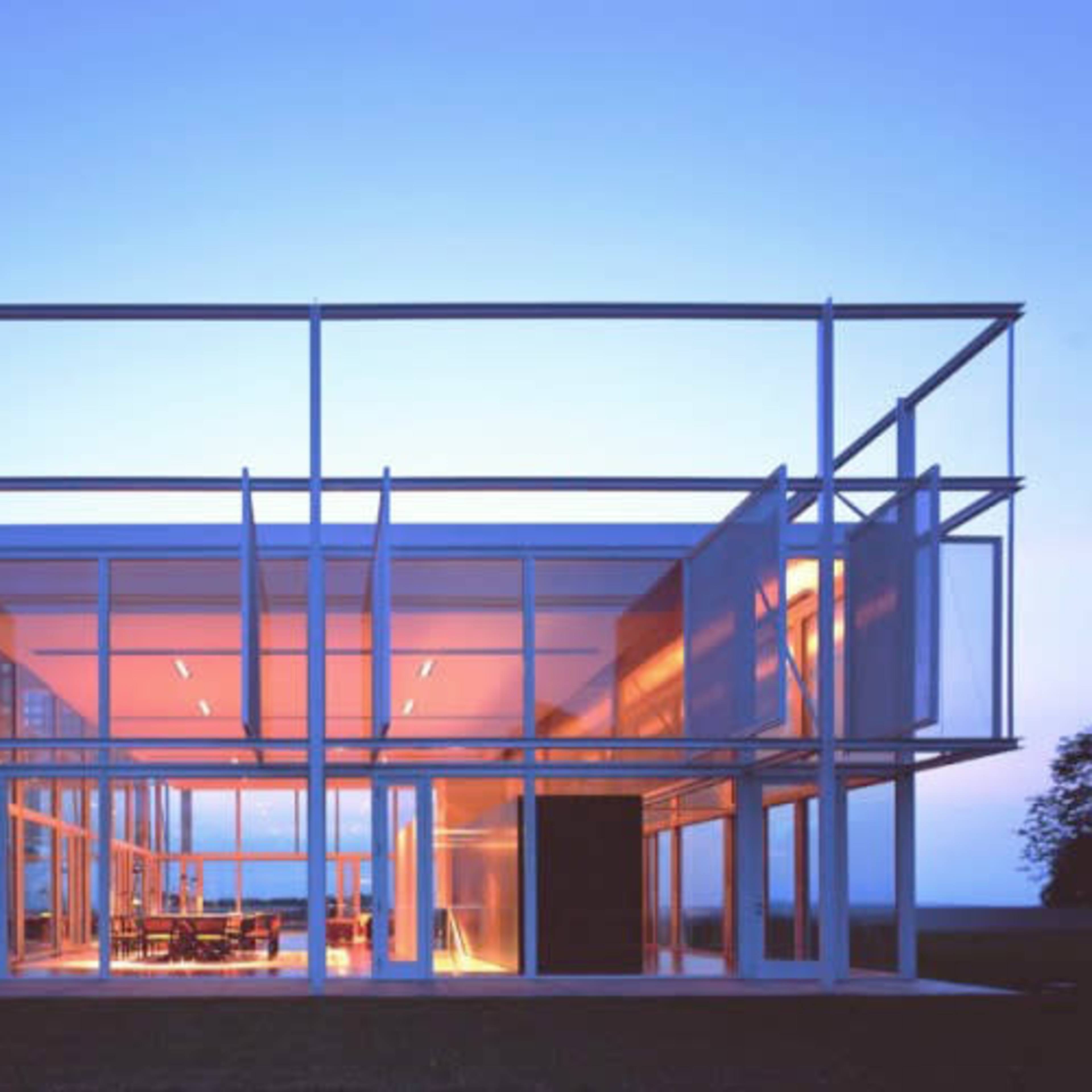 A modern glass-and-steel building with a grid-like structure illuminated at dusk.