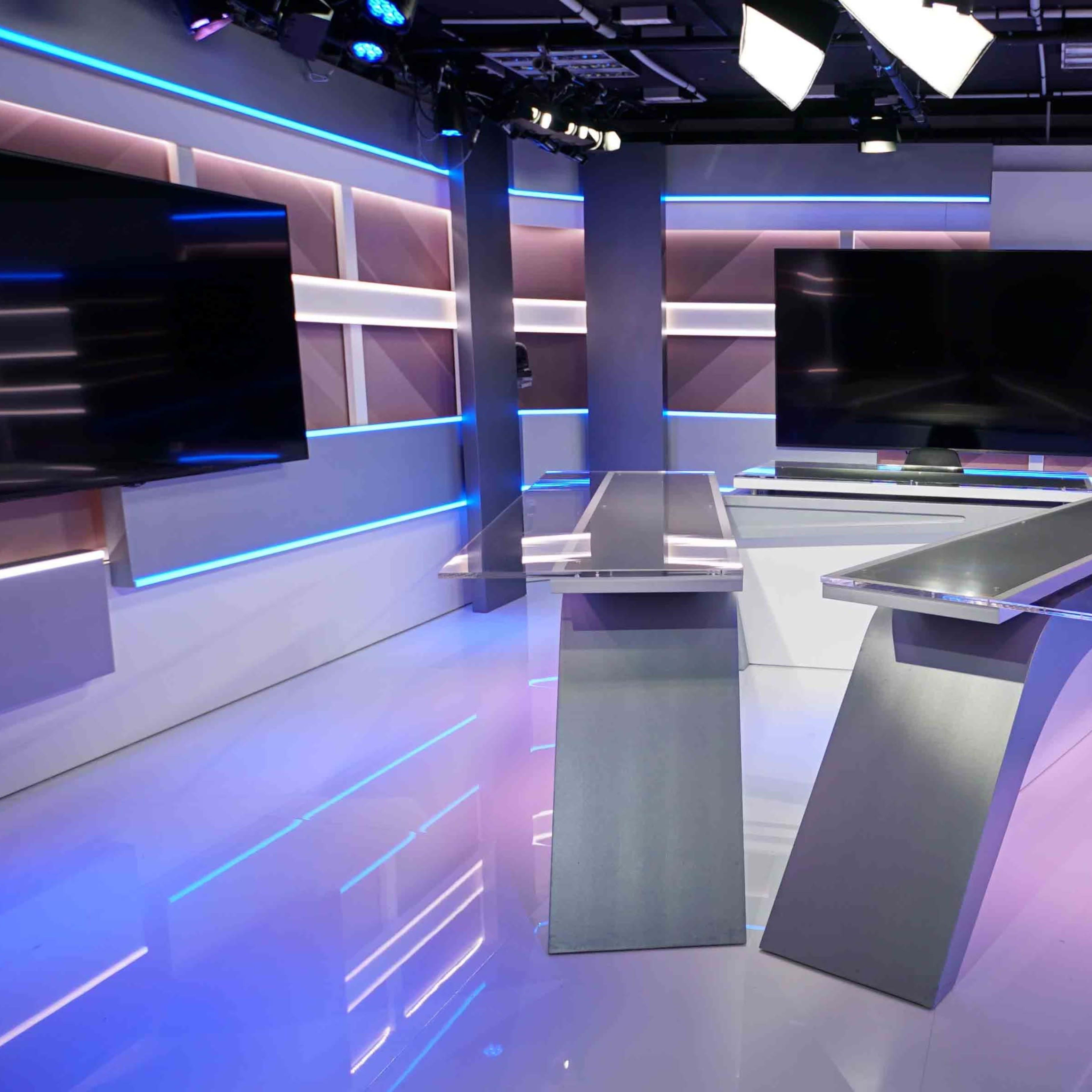 A modern television news studio with sleek, minimalist furniture and illuminated shelving.