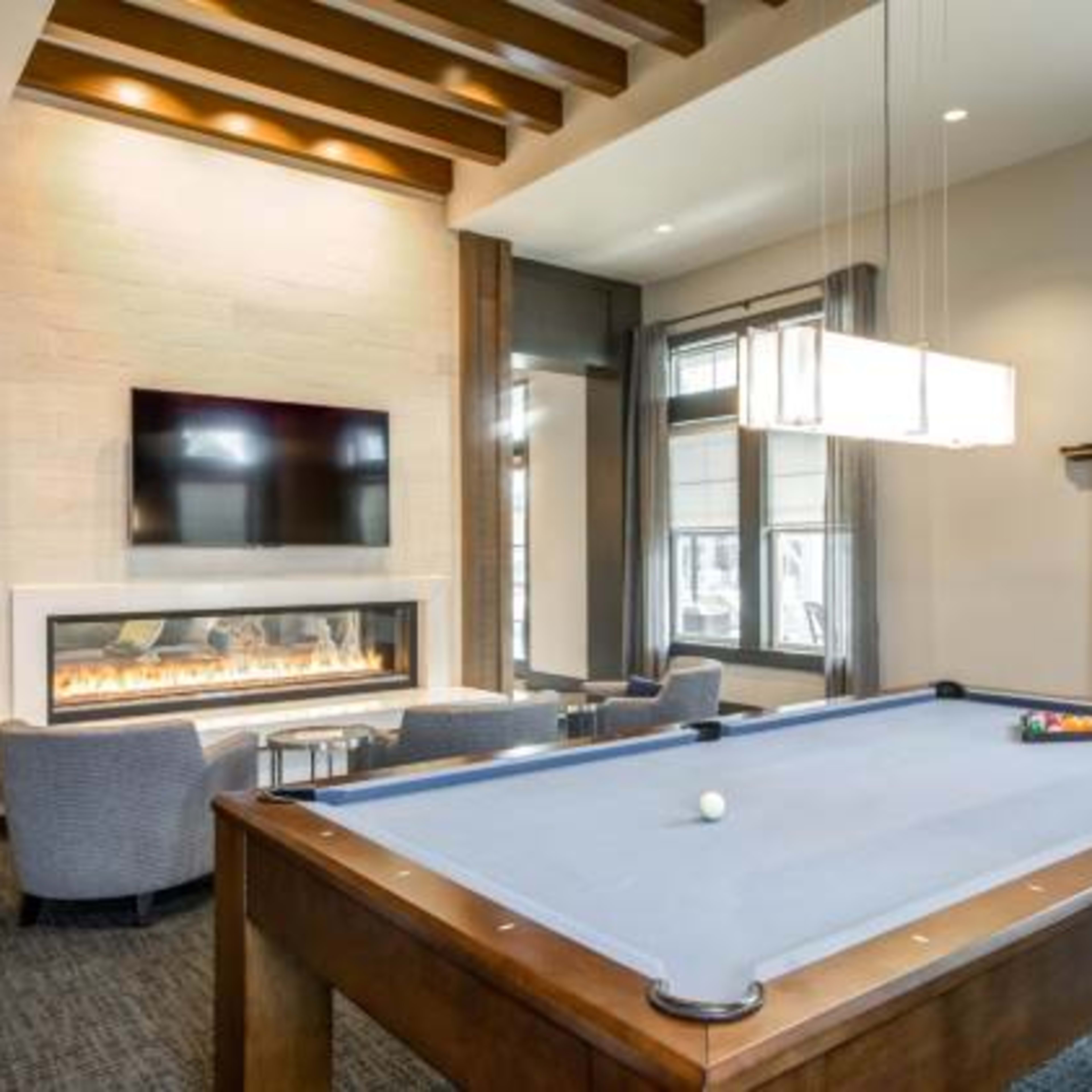 A modern room featuring a billiard table, a fireplace, and a television mounted on the wall.