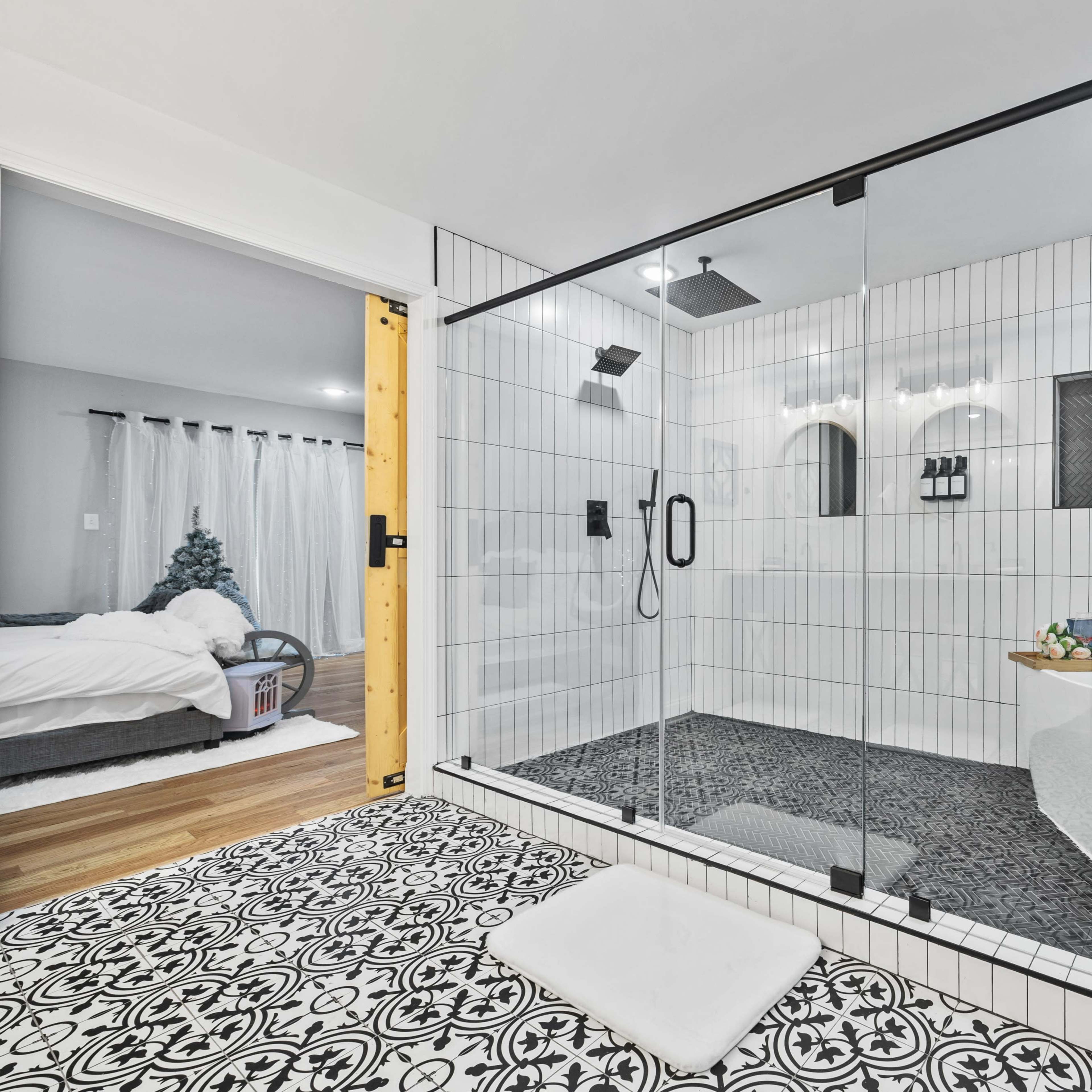 A modern bathroom features a glass shower enclosure, a freestanding tub, and patterned tile flooring.