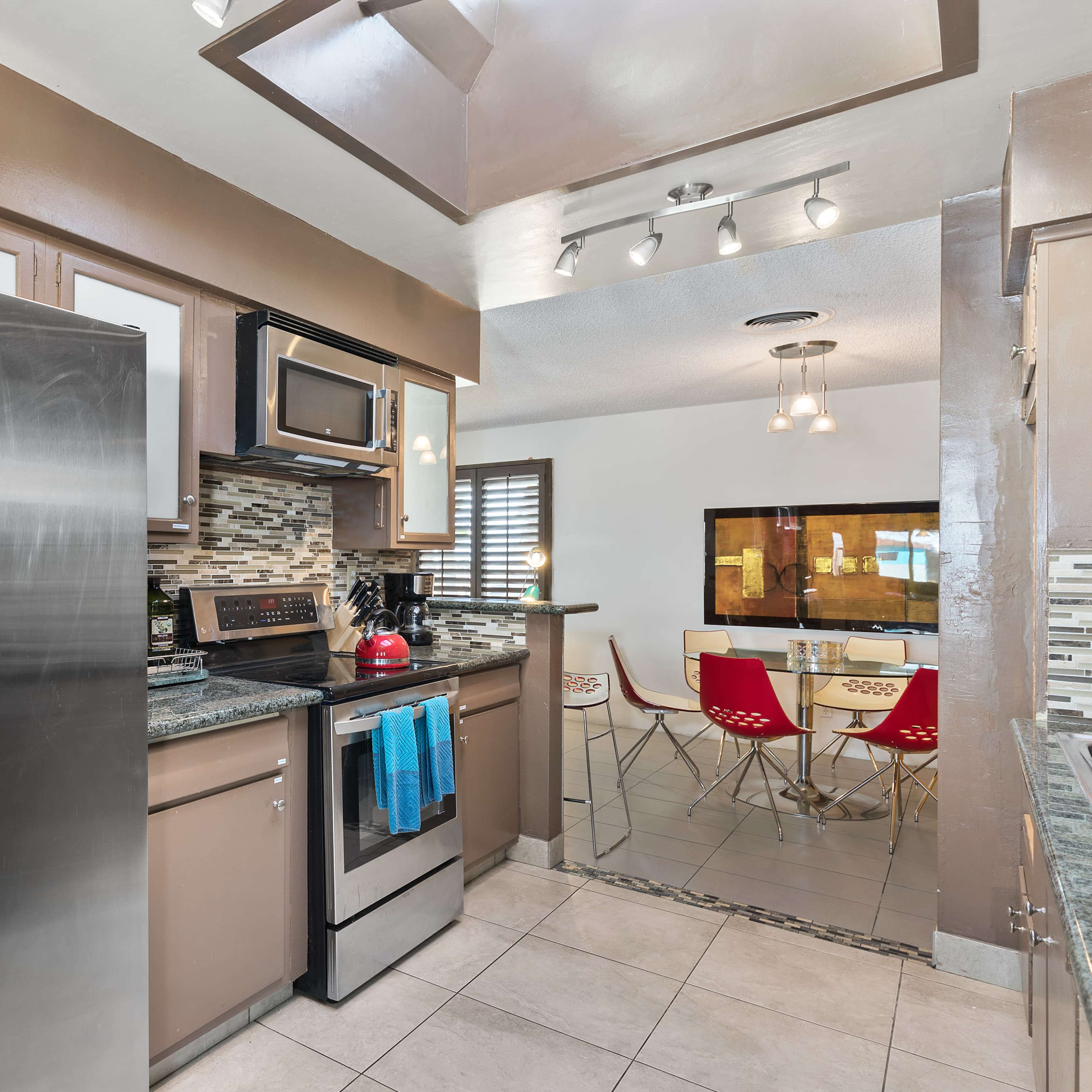 A modern kitchen with stainless steel appliances, granite countertops, and a dining area visible in the background.