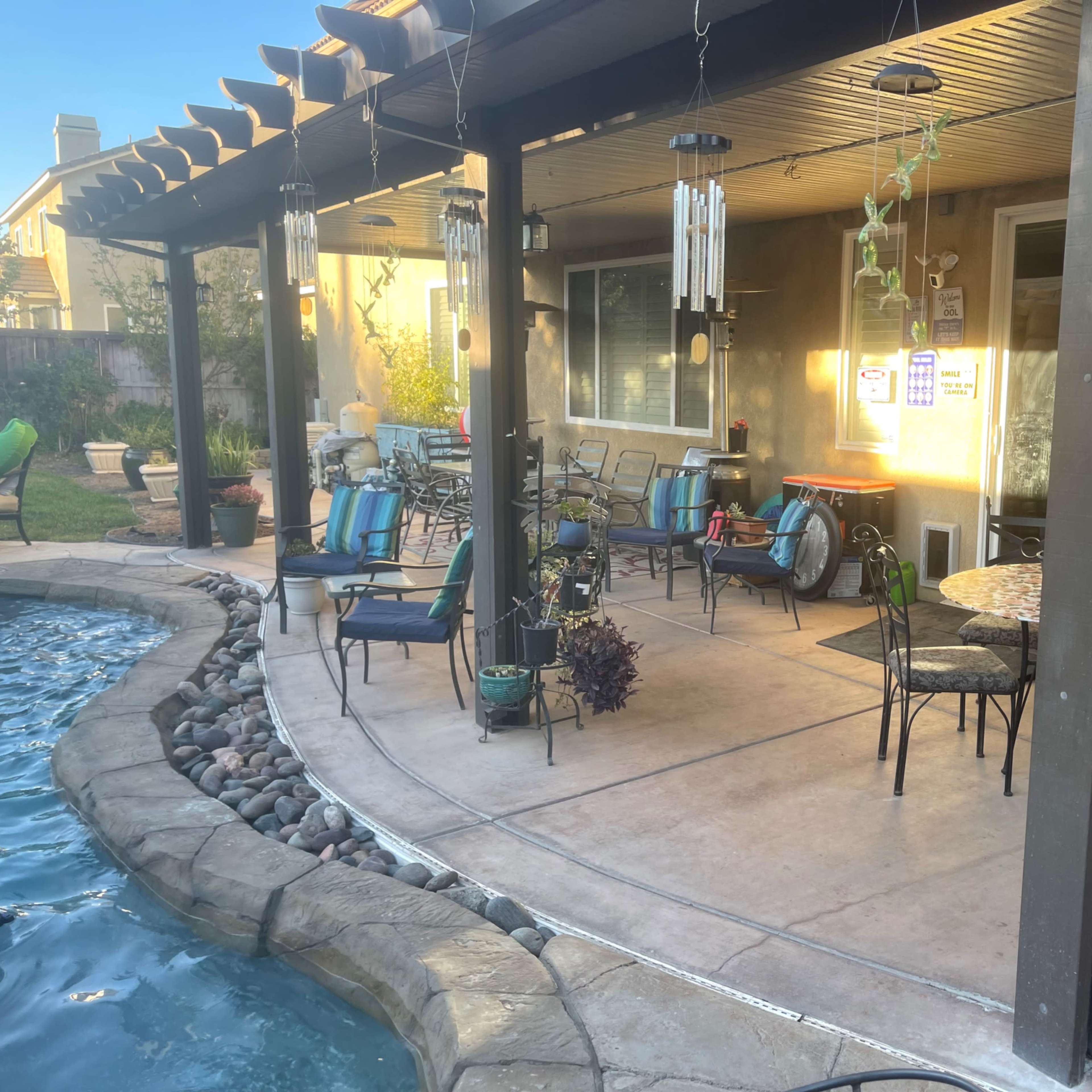 A patio area with several chairs and tables set up alongside a swimming pool.