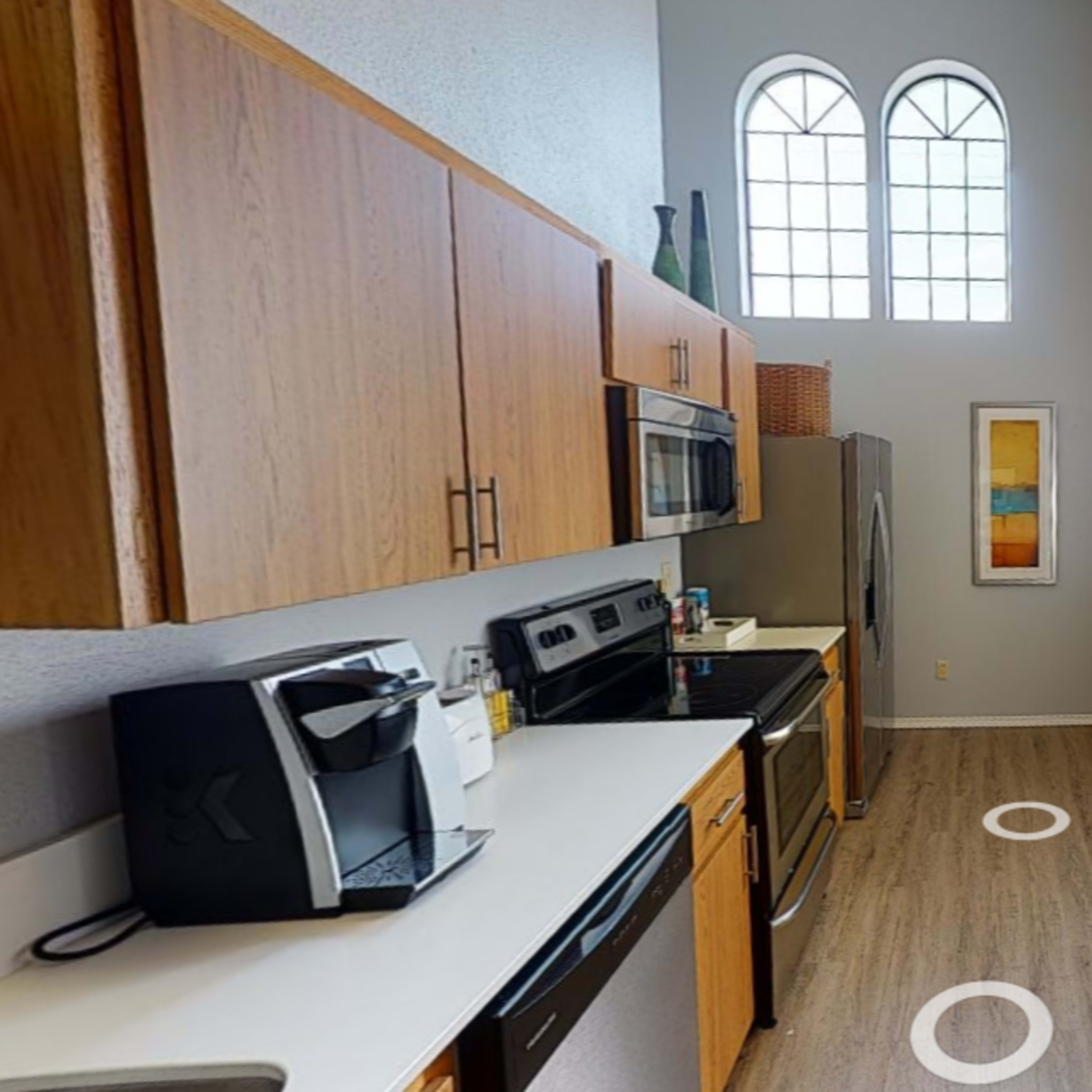 A modern kitchen with wooden cabinets, stainless steel appliances, and a large wall art piece.
