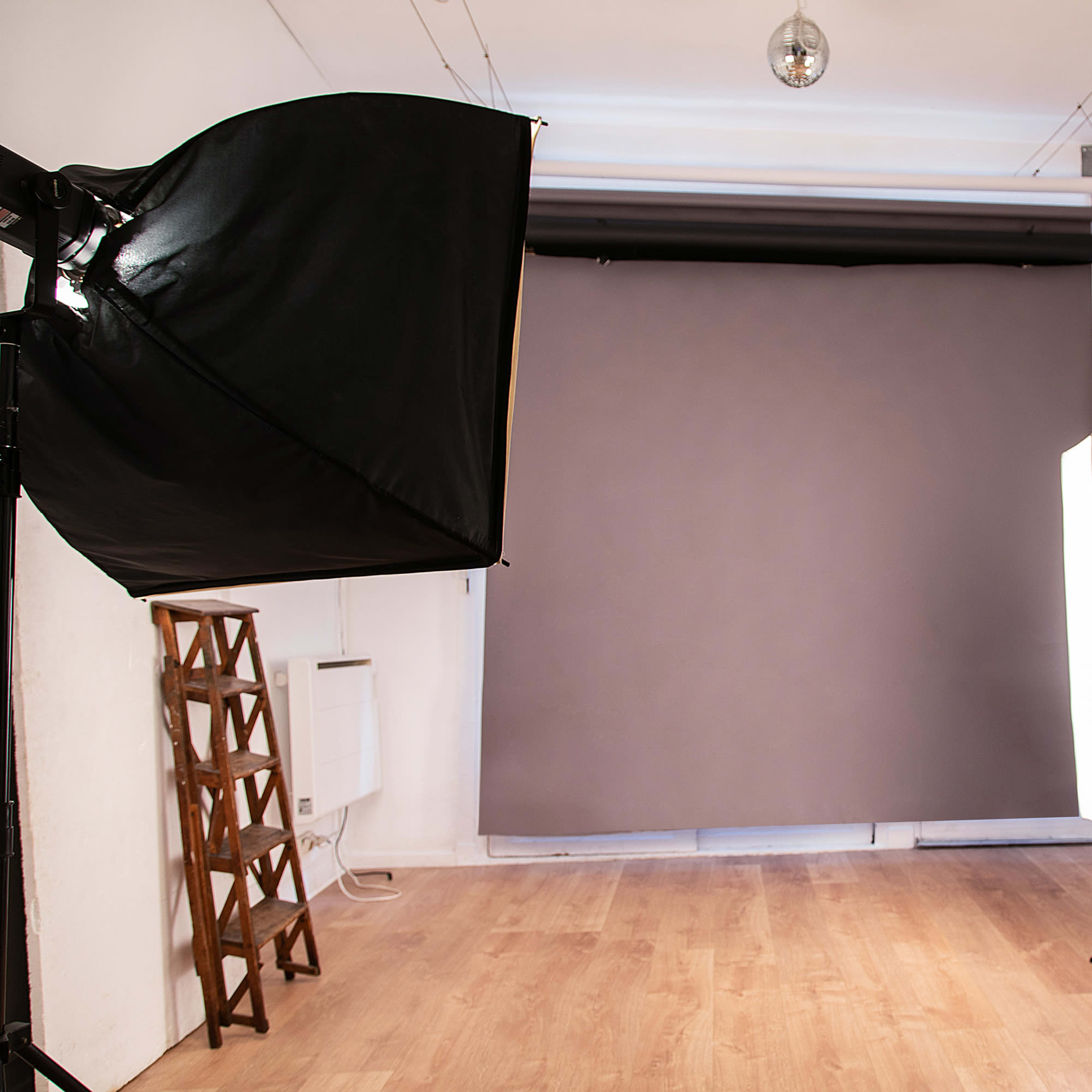 A photography studio with two large softbox lights positioned on either side of a neutral gray backdrop.