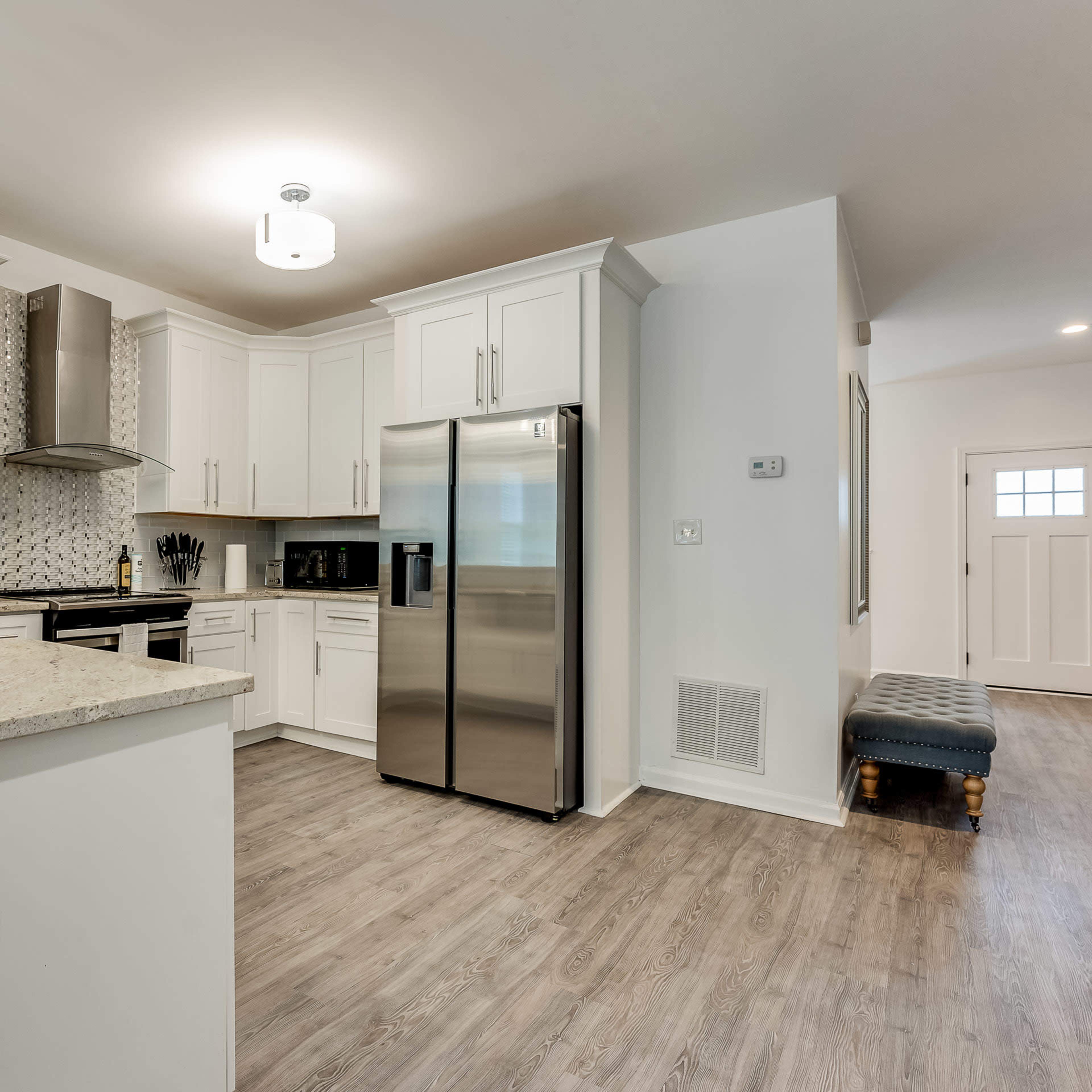 A modern kitchen with white cabinetry, stainless steel appliances, and a granite countertop.