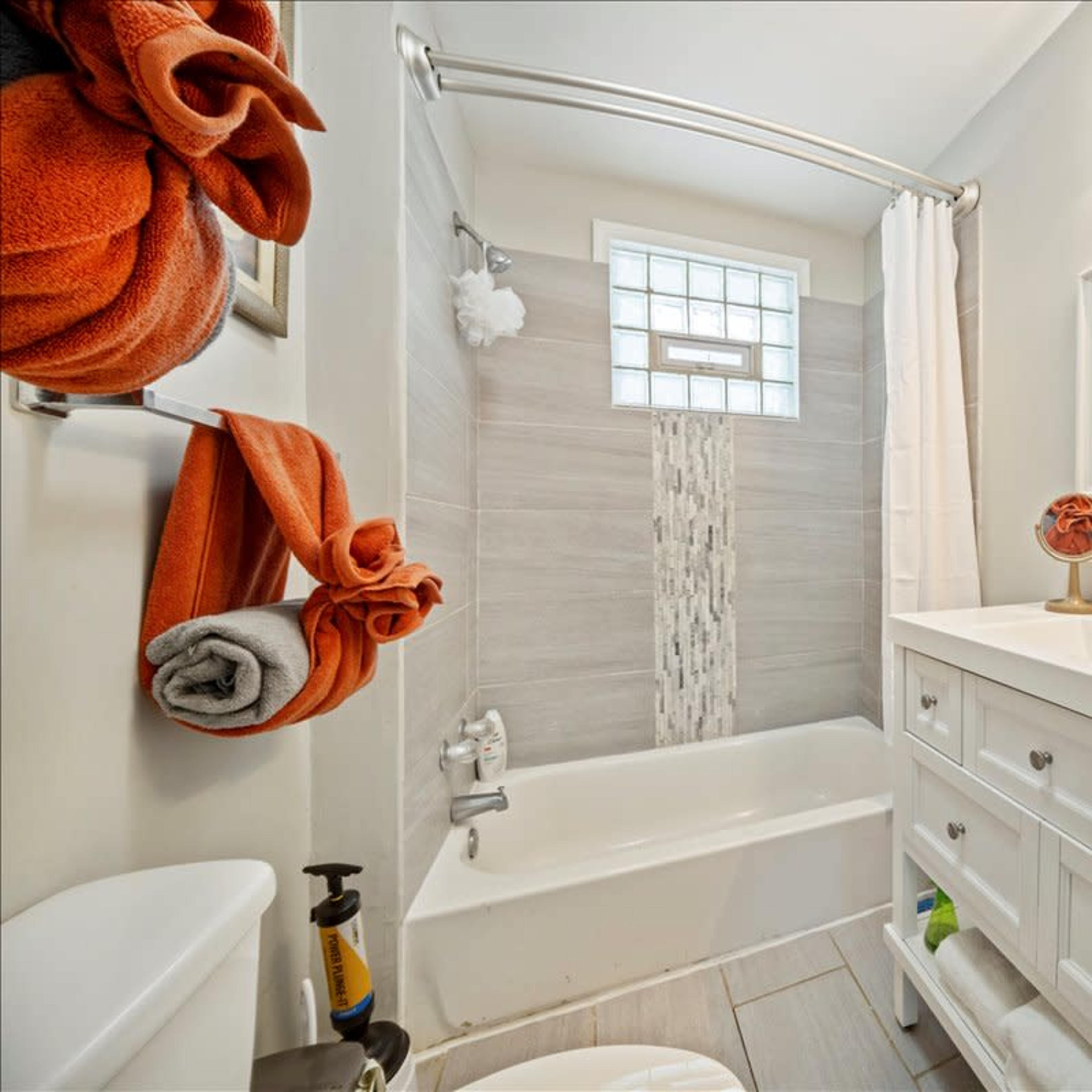 A compact bathroom featuring a bathtub with a shower curtain, a white sink vanity, and neatly arranged towels on a rack.
