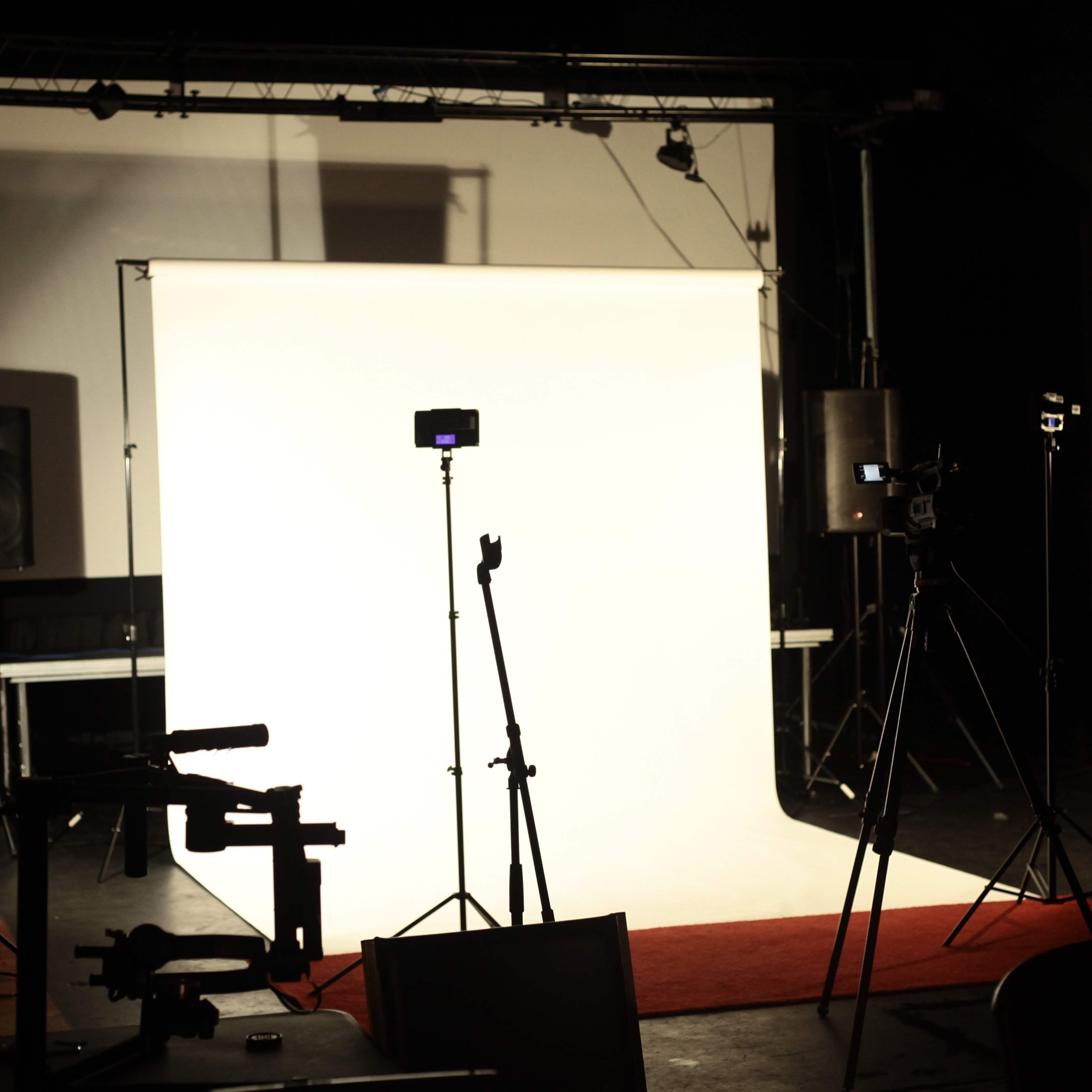 A photography studio is set up with a white backdrop and multiple lights on tripods arranged around the space.