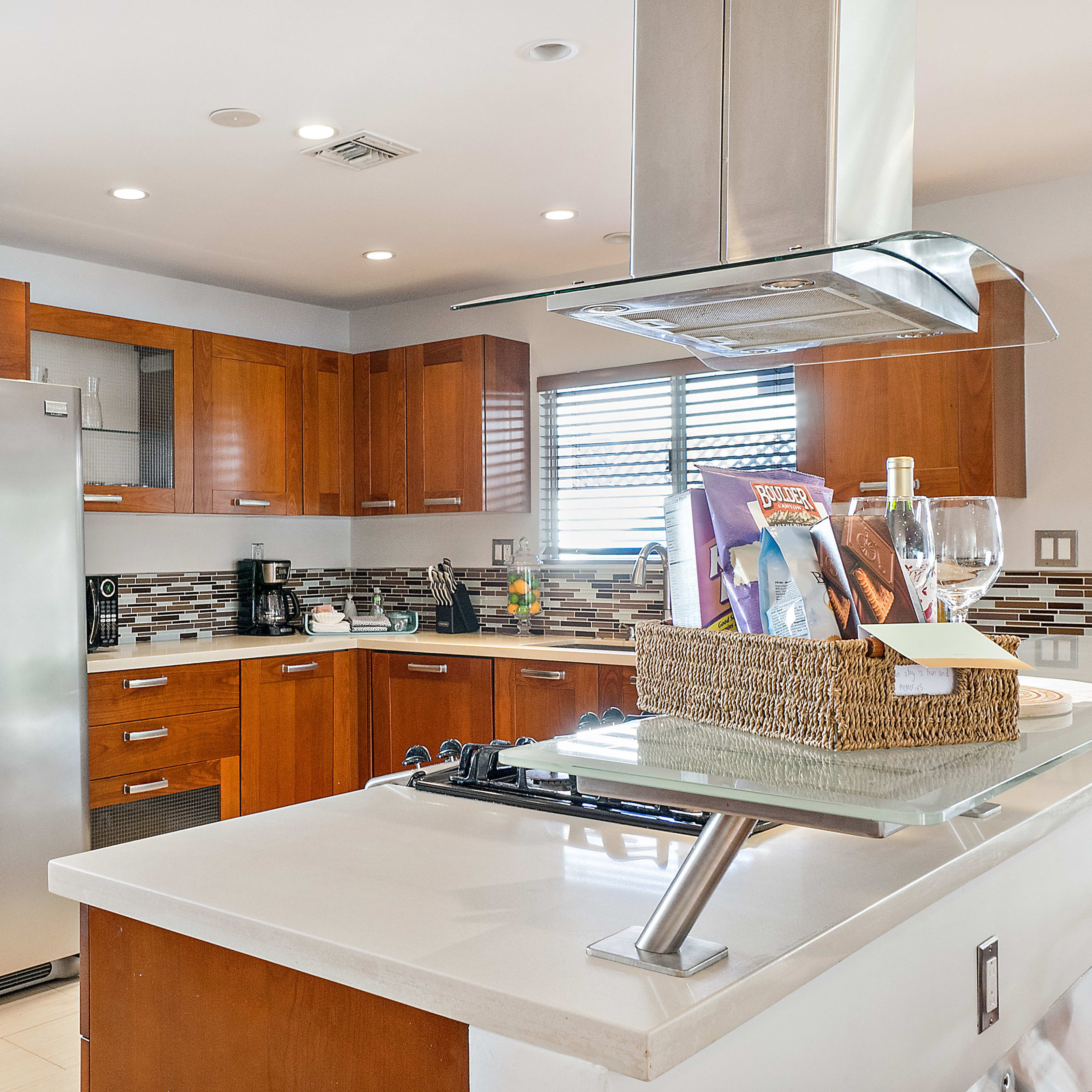 A modern kitchen featuring wooden cabinetry, stainless steel appliances, and a countertop with a basket of items.