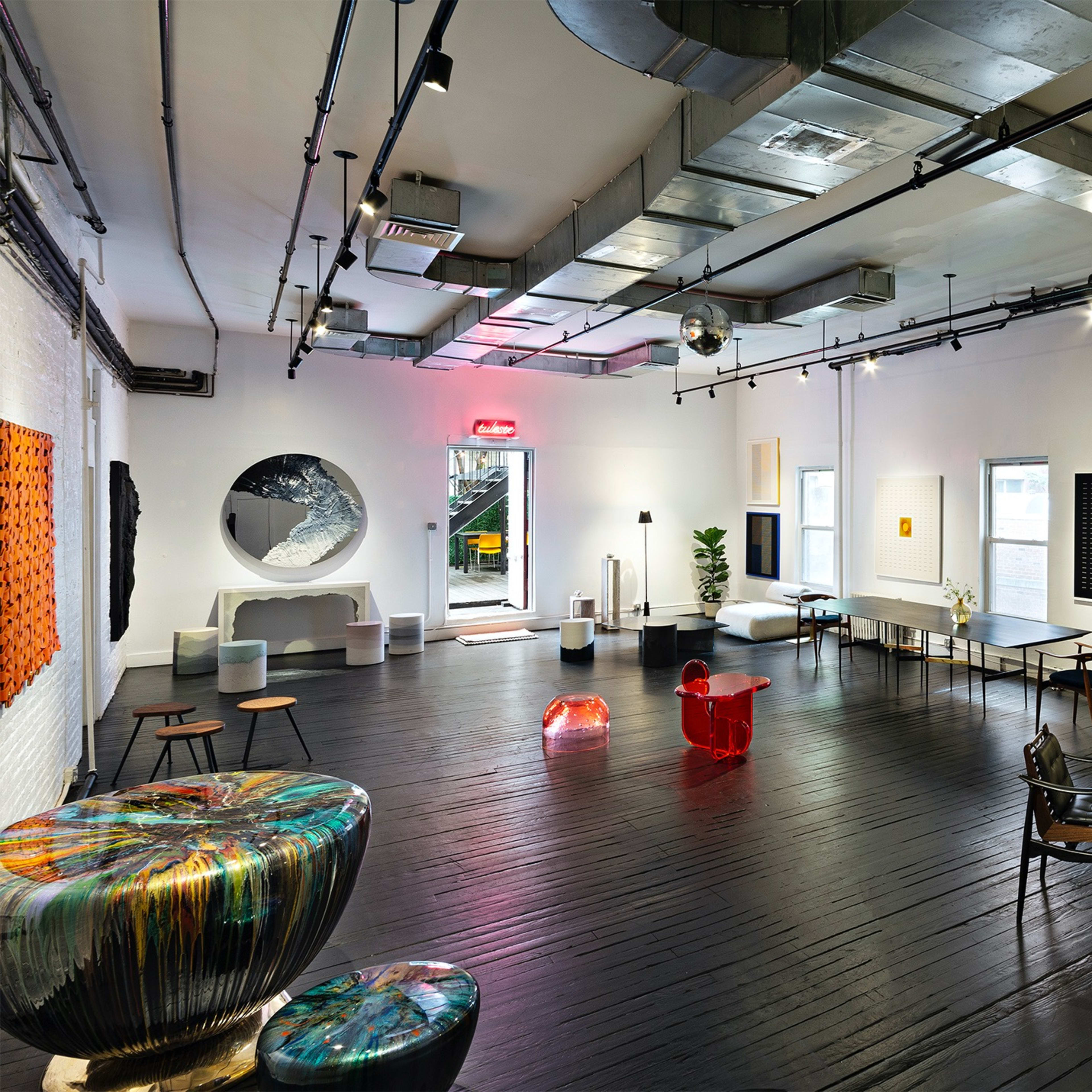 A modern art gallery featuring various artworks on the walls, stylish seating arrangements, and a polished wooden floor.