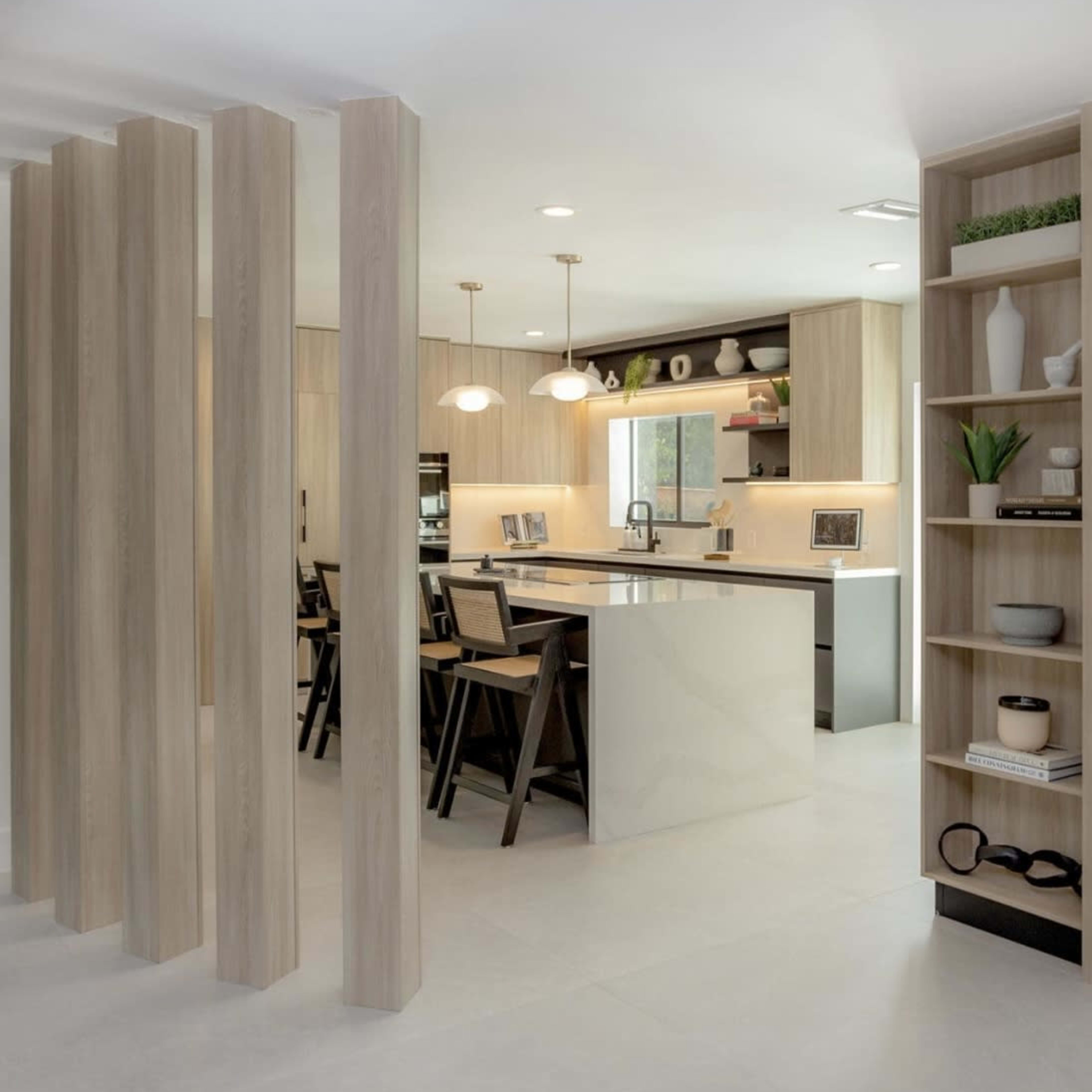 A modern kitchen and dining area feature wooden pillars, sleek cabinetry, and an island with seating.