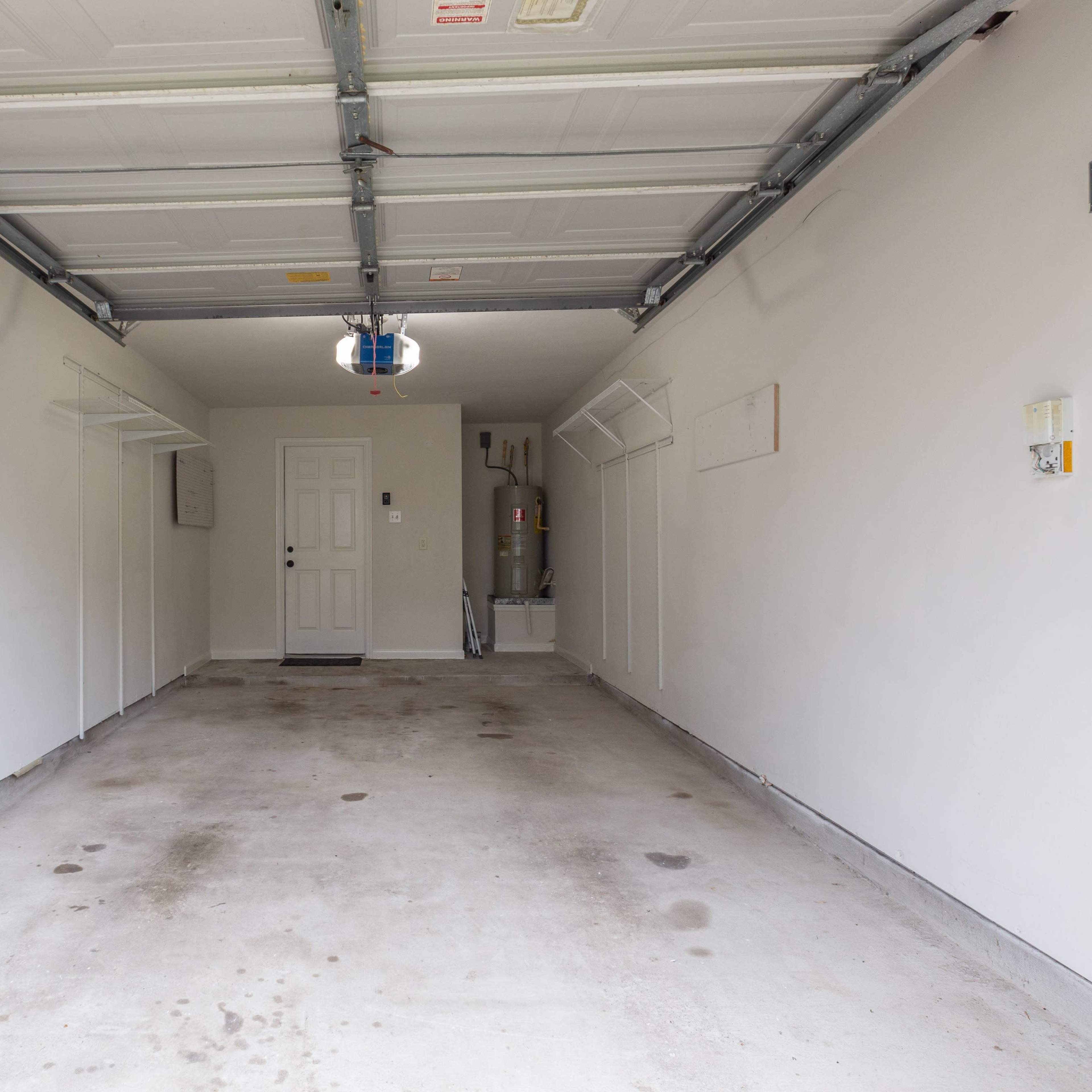 An empty garage with a concrete floor, a closed overhead door, and minimal storage on the walls.