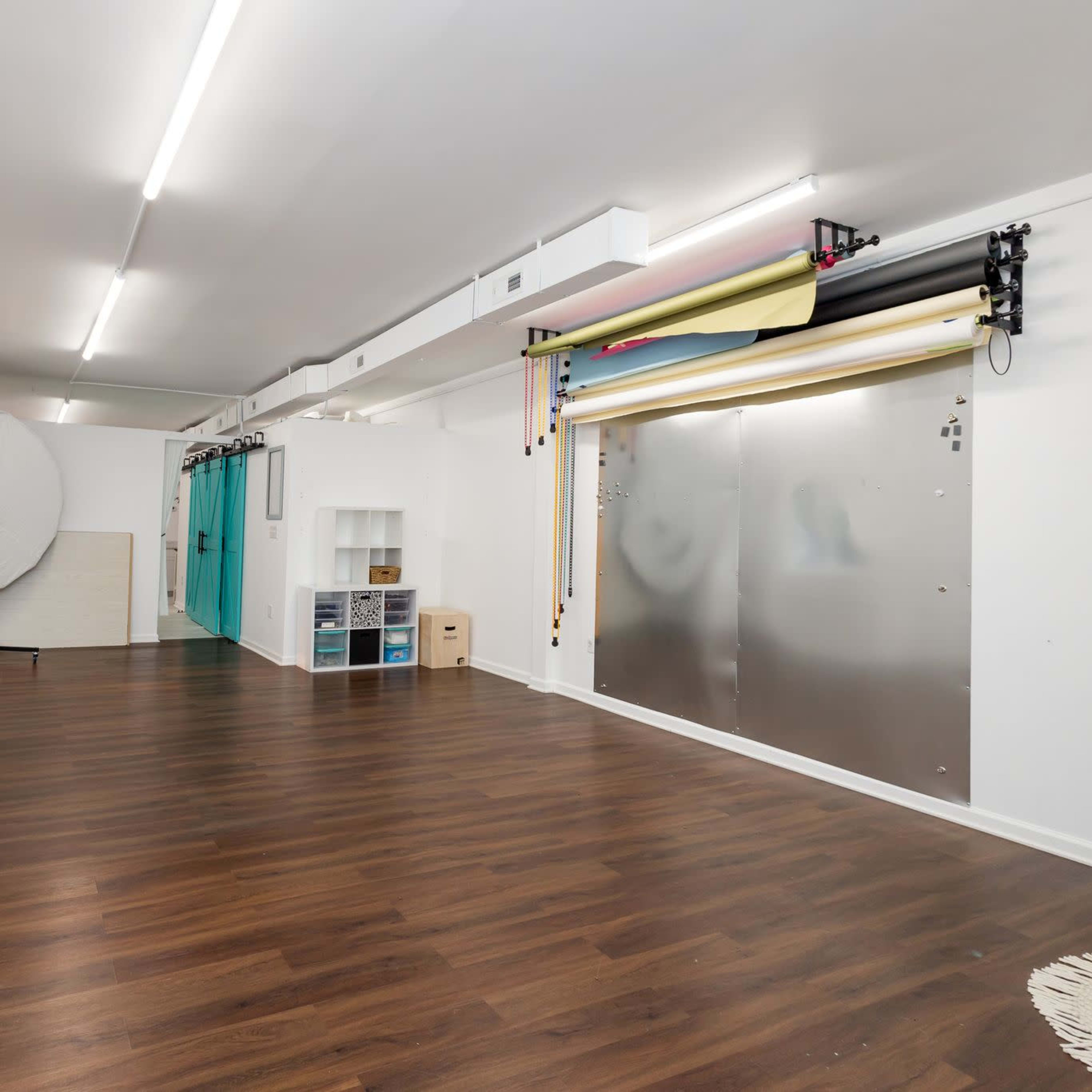 A spacious room with wooden flooring, a round backdrop, and a setup for various colored backgrounds along one wall.