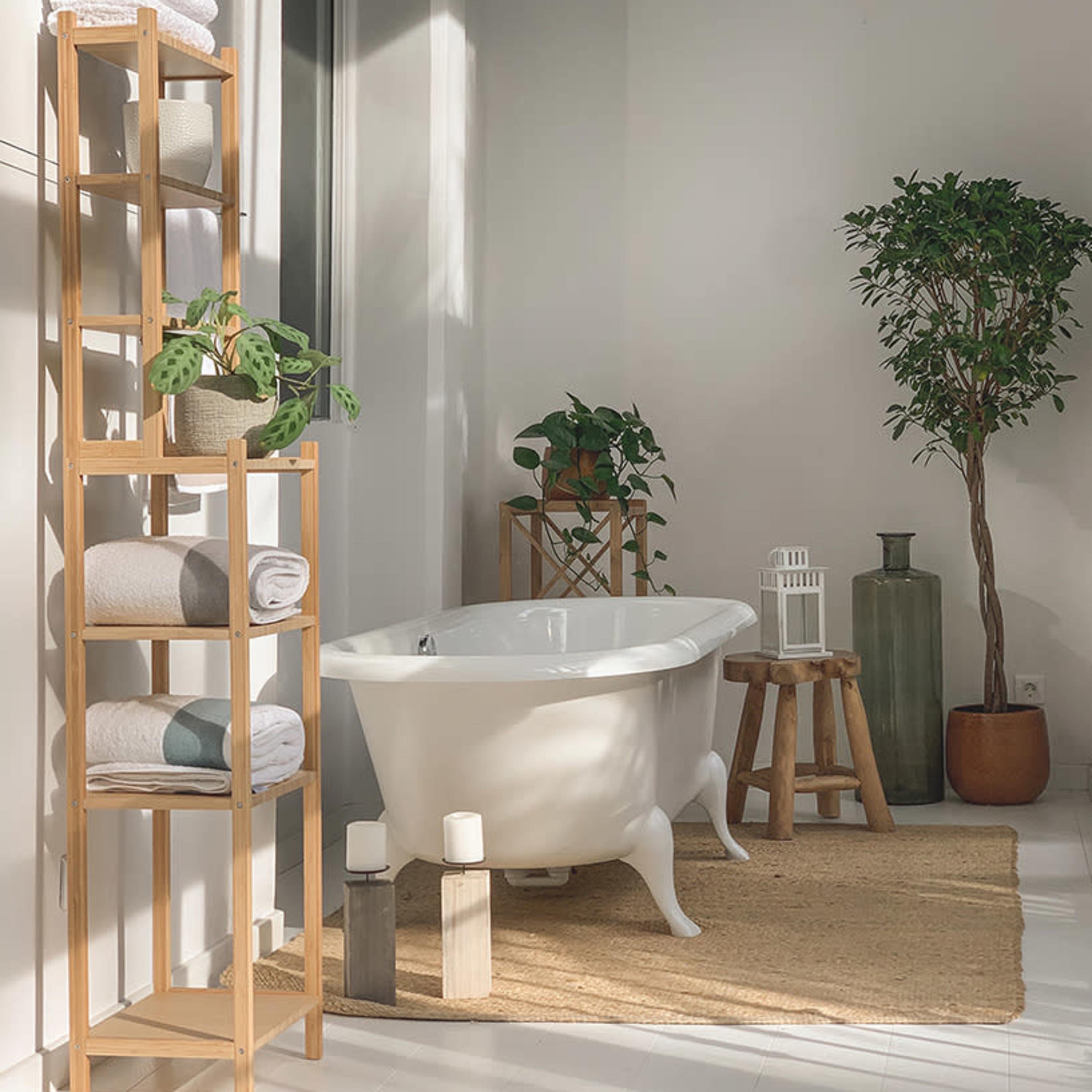The scene features a bright bathroom with a freestanding white bathtub, a wooden shelf holding towels, and potted plants near a woven rug.
