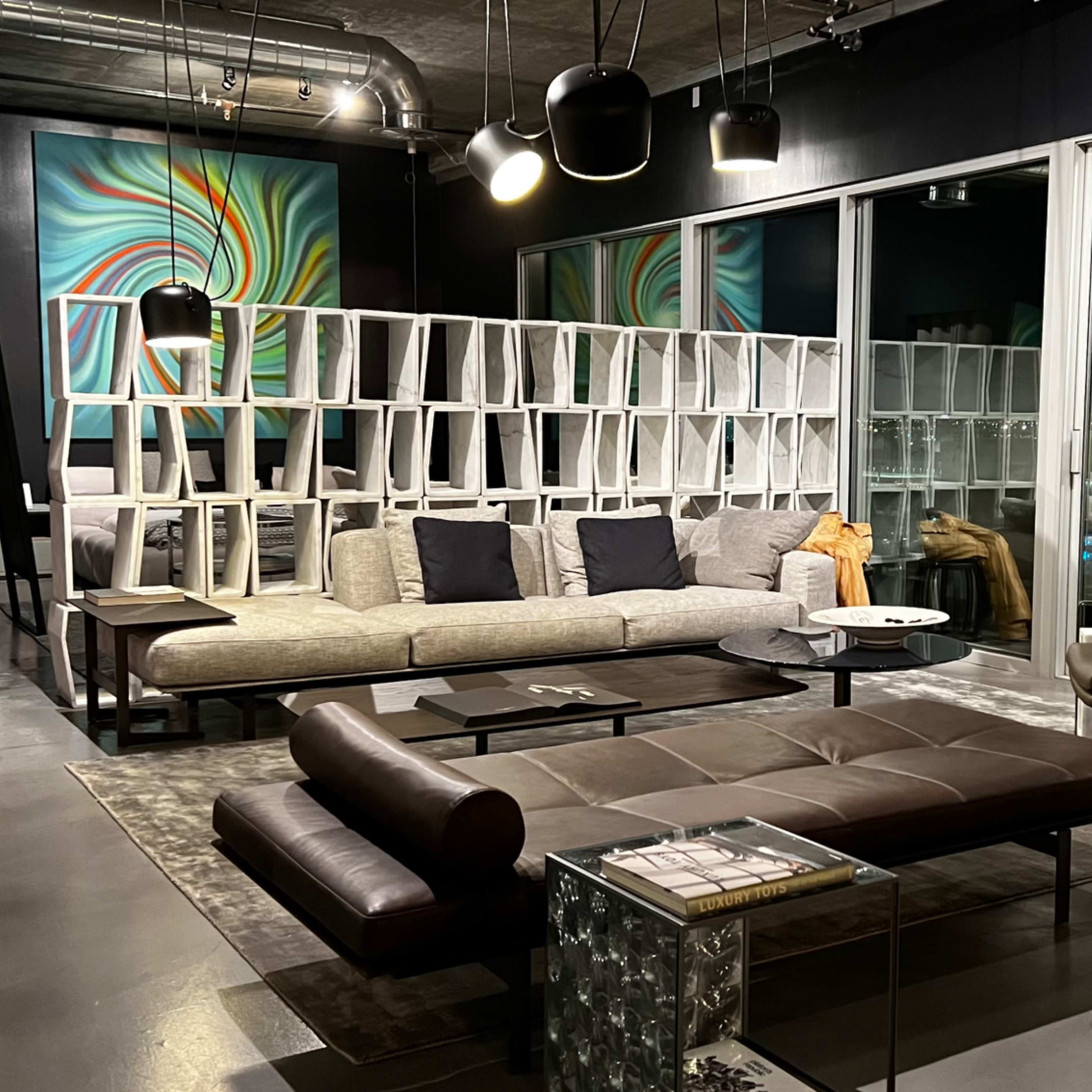 A modern living room featuring a sectional sofa, a coffee table, and large windows with city views, all arranged in a stylish, open space.