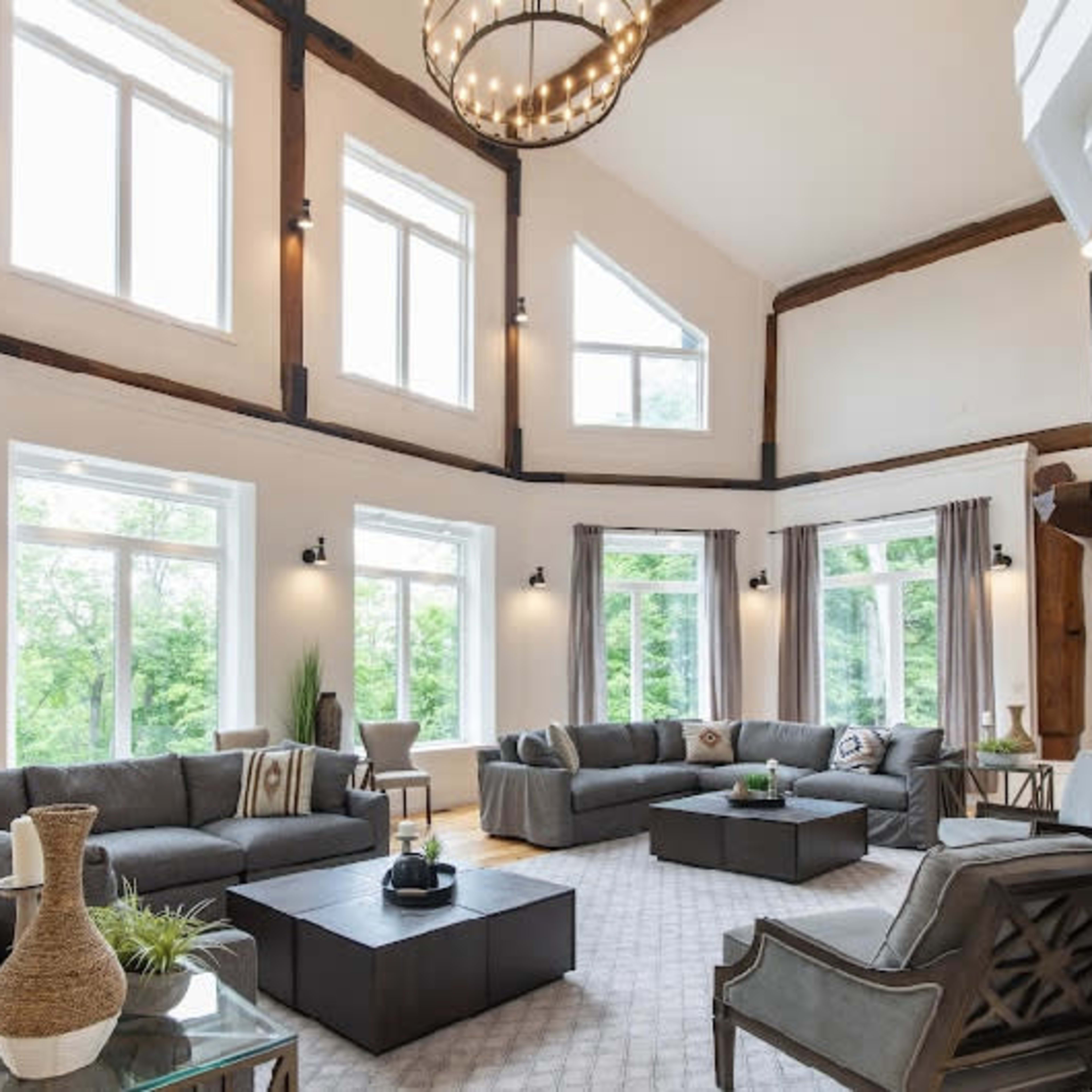 A spacious living room with large windows, multiple seating areas, and a central coffee table.