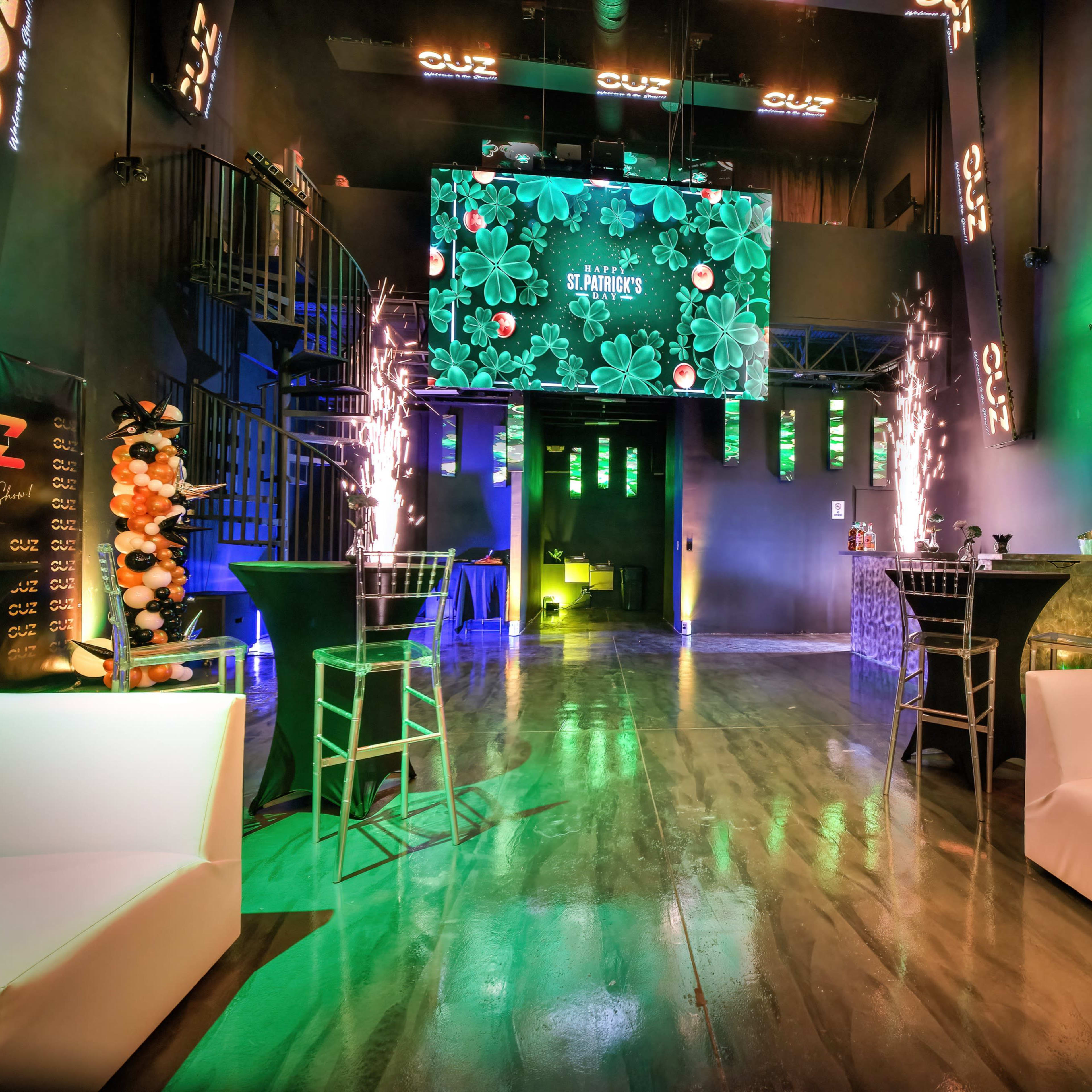 The scene shows a modern event space with a large screen display, seating areas, and decorative lighting elements.