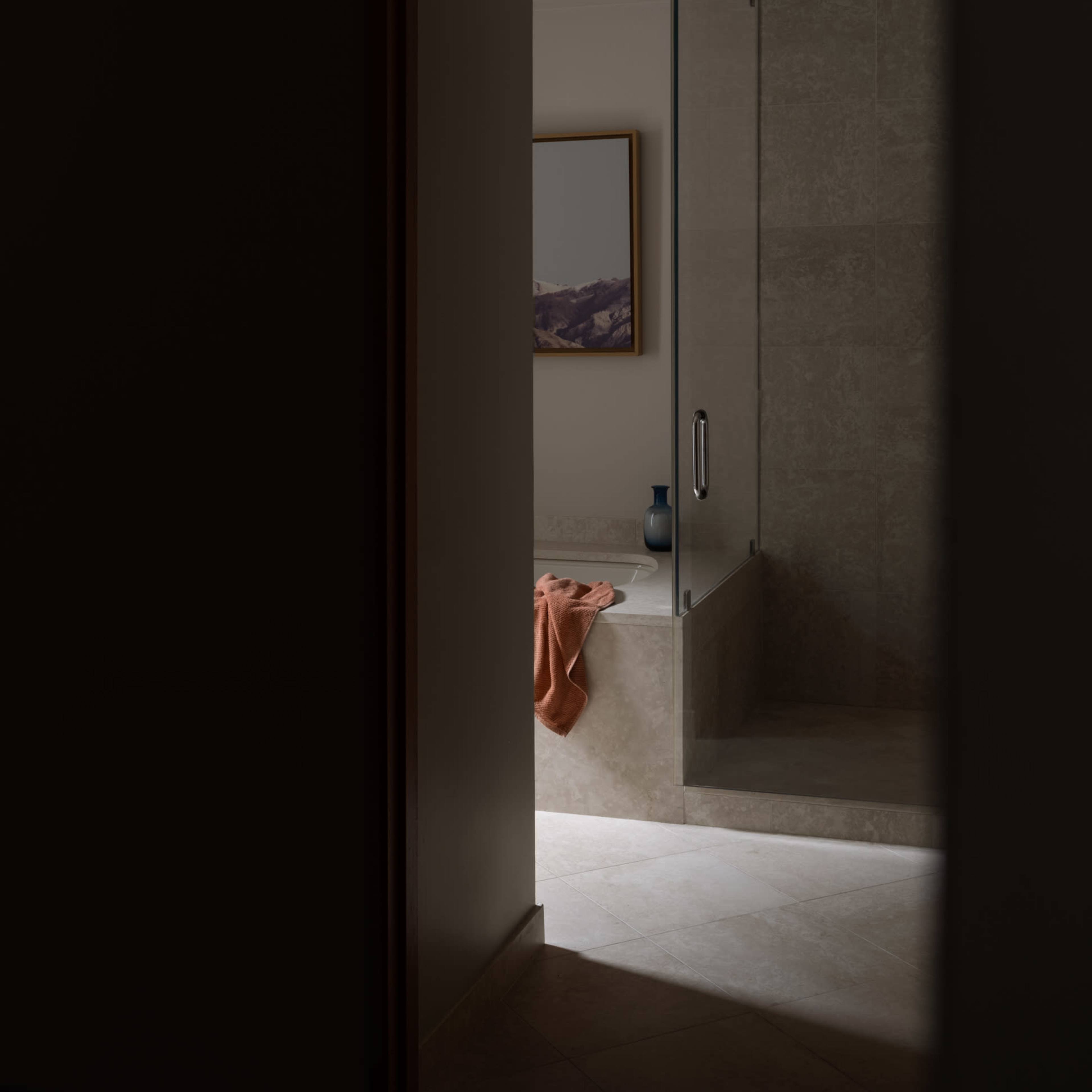 A bathroom interior features a shower enclosure and a bathtub with a towel draped over the edge.