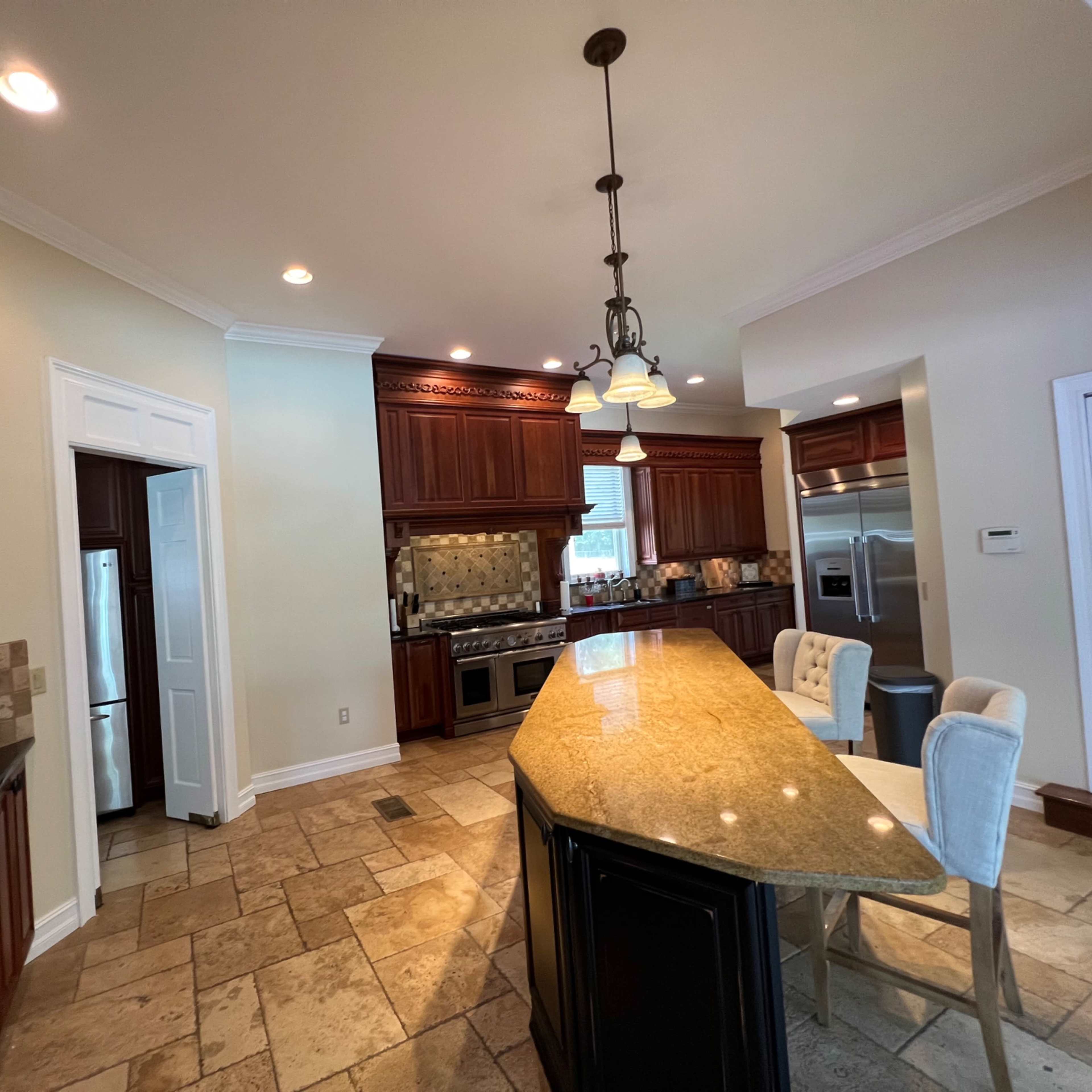 A spacious kitchen features wooden cabinetry, an island with seating, and stainless steel appliances.