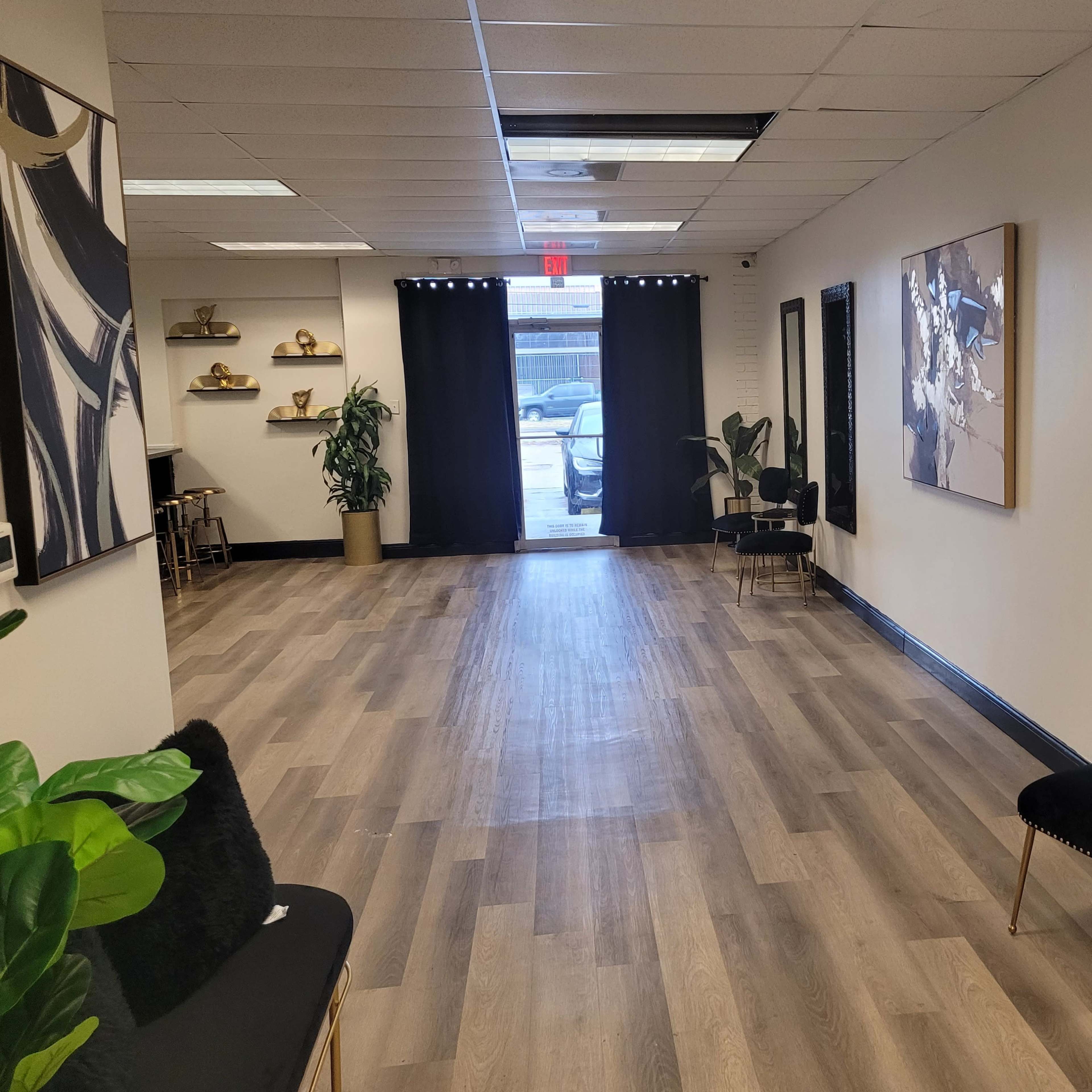 A spacious, well-lit hallway with wooden flooring, featuring black curtains at the entrance and modern decor on the walls.