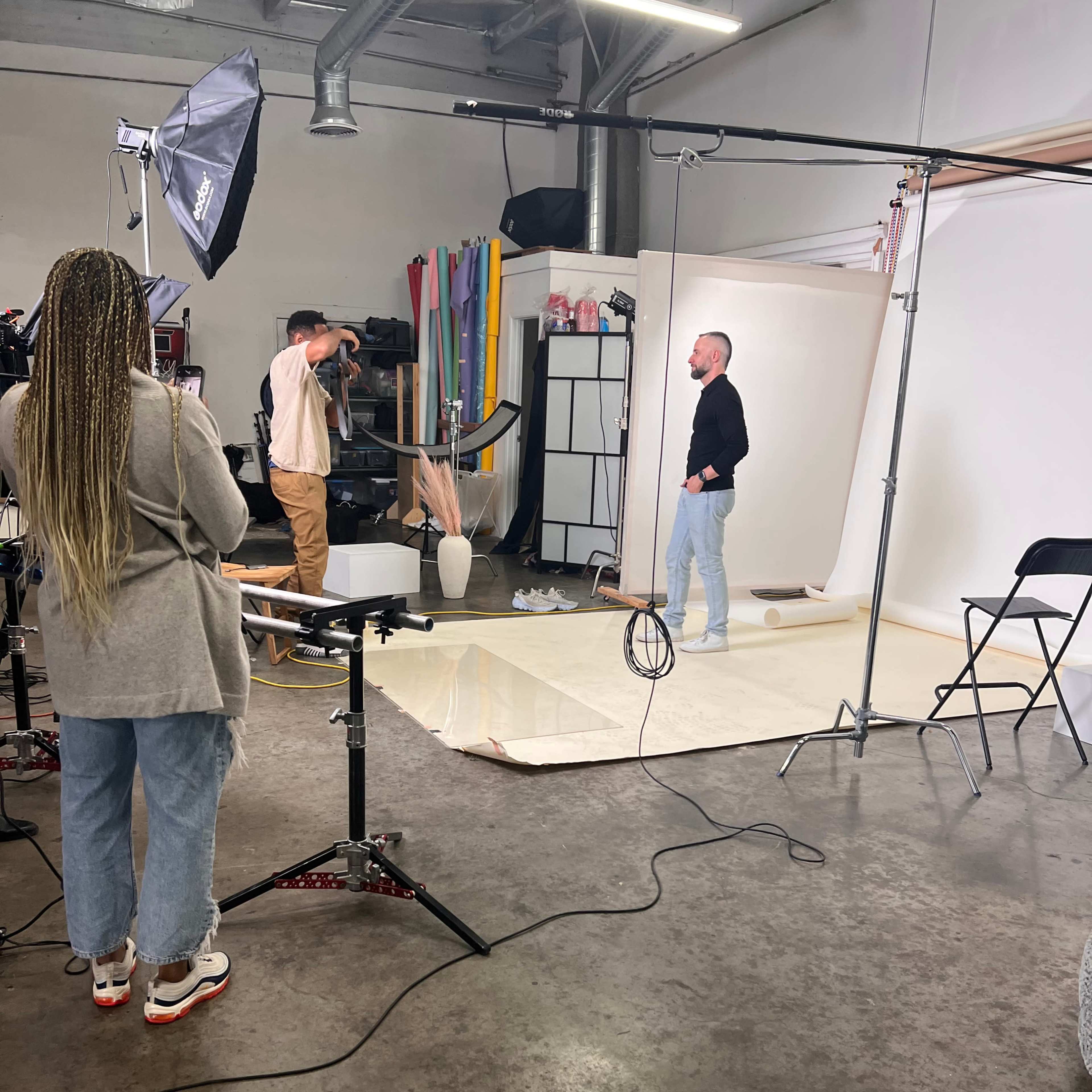 A photographer captures a subject in a studio setting with multiple backdrops and lighting equipment.