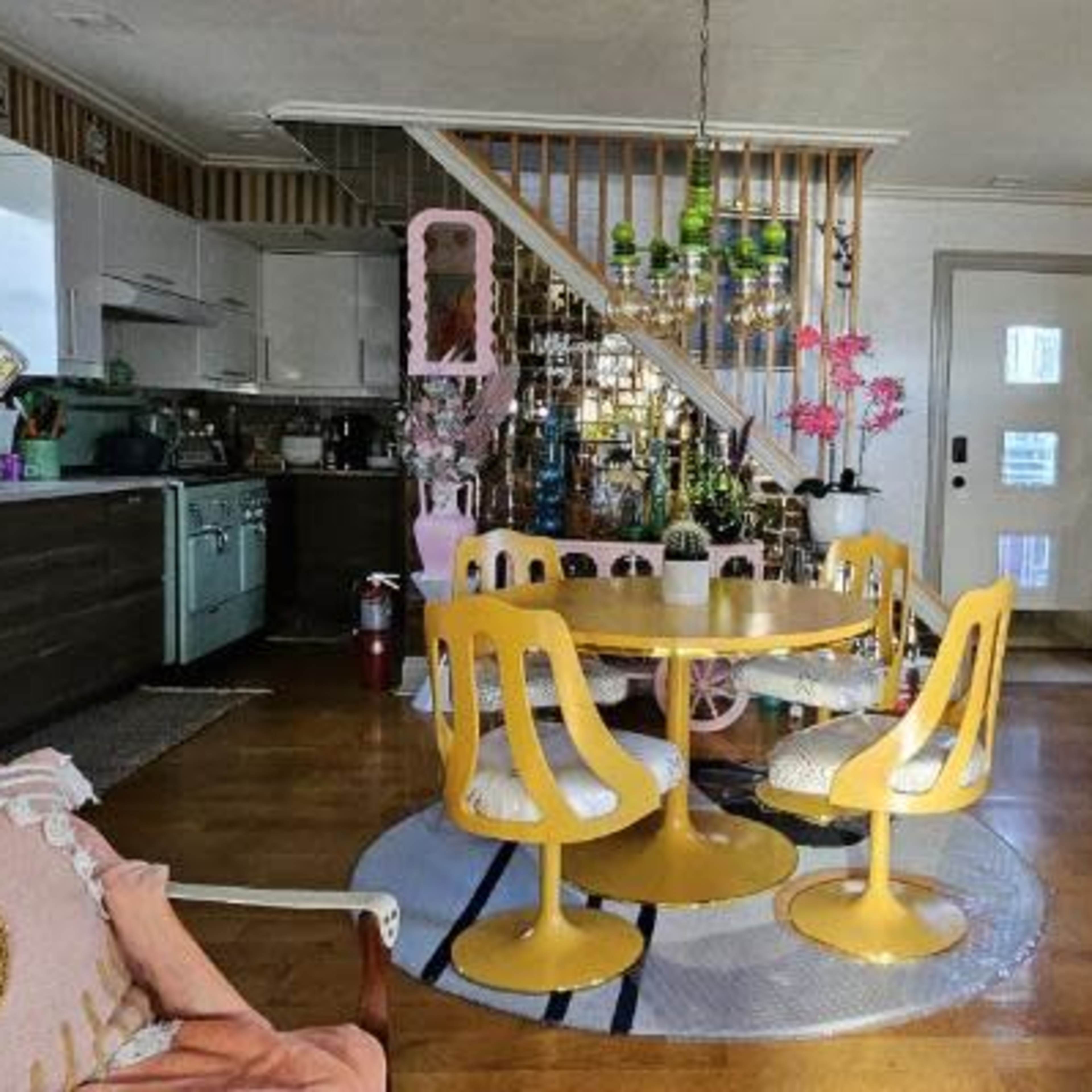 A colorful living space featuring a yellow circular dining table with matching chairs, a white sofa, and various decorative items throughout the room.