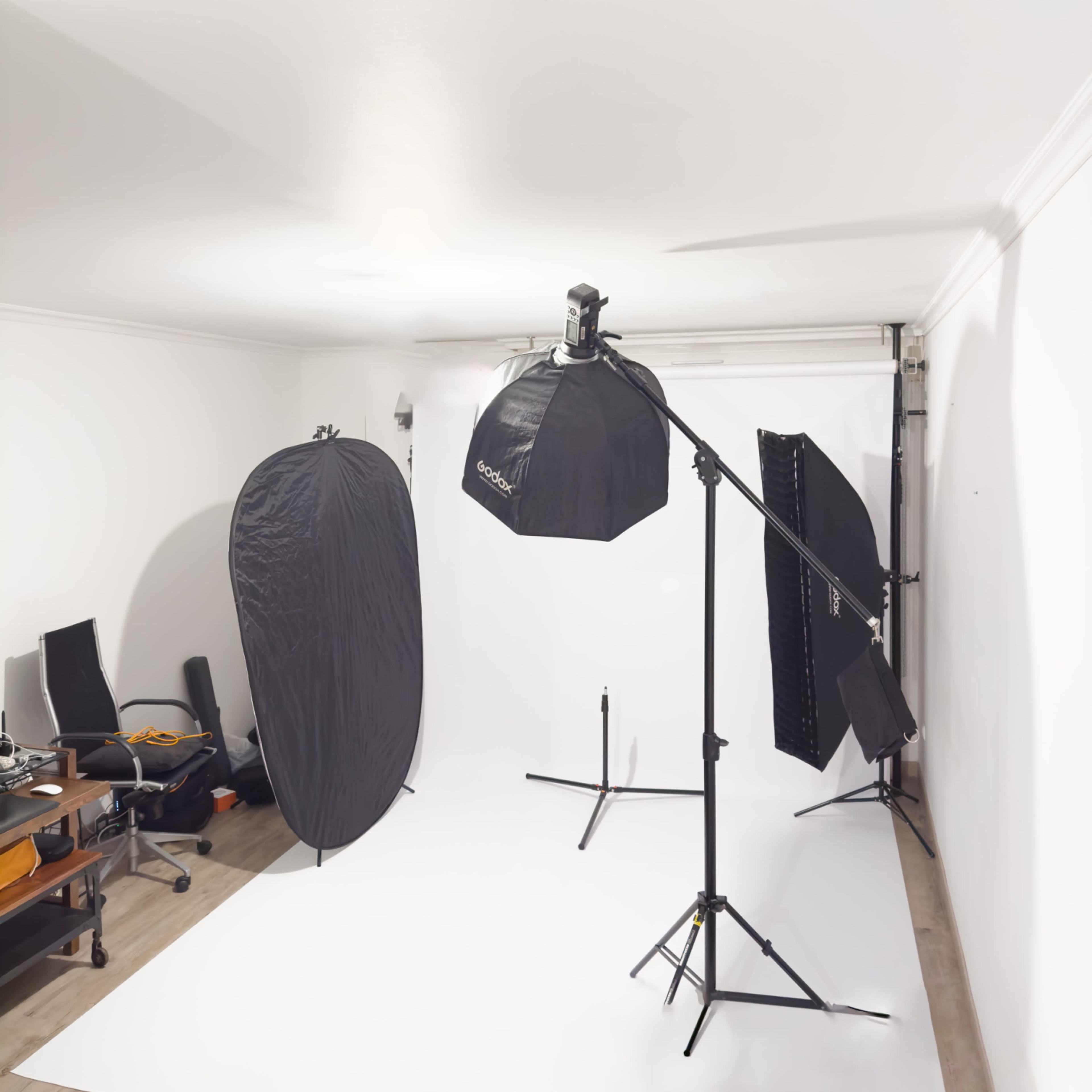 A photography studio with lighting equipment and backdrops set up on a white backdrop.