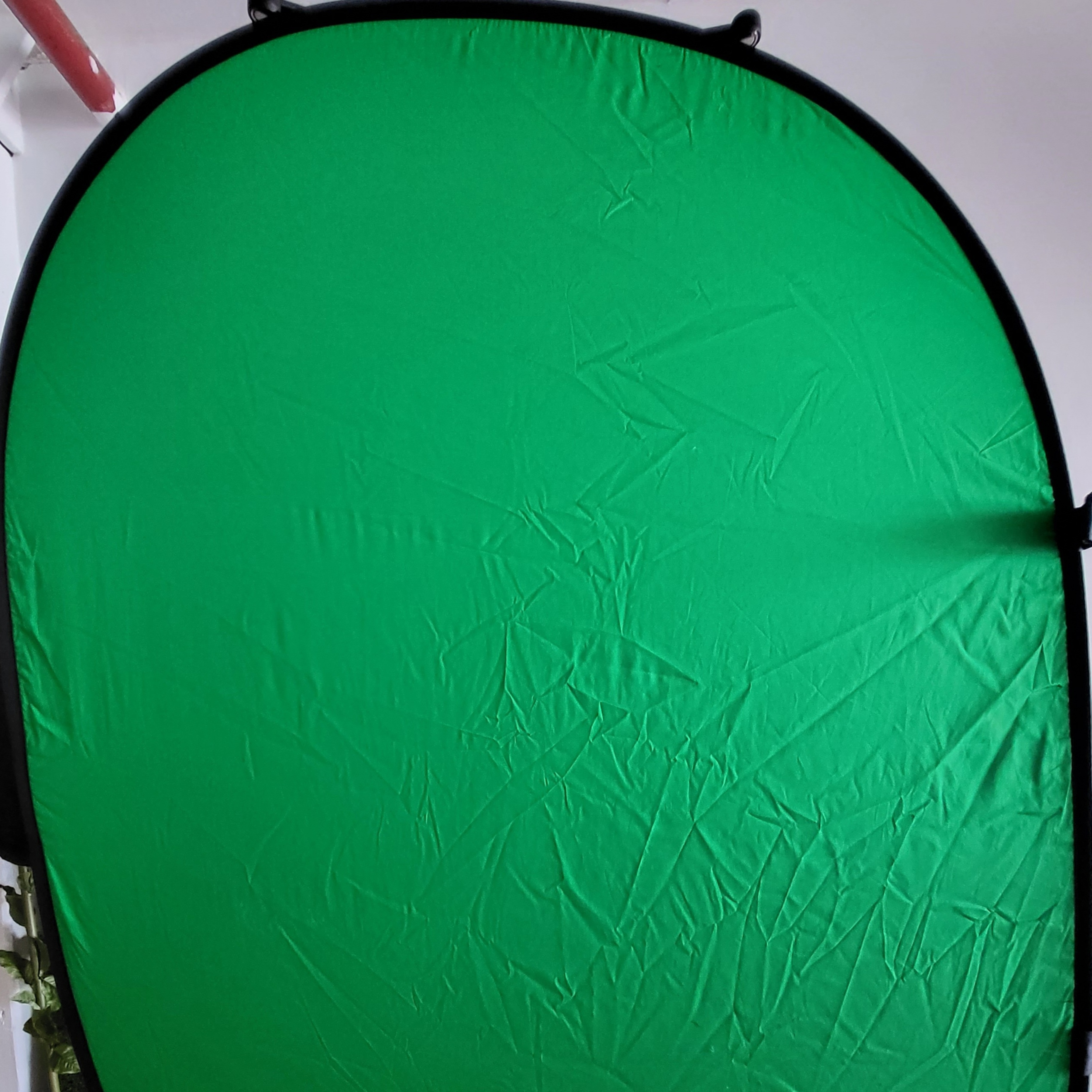 A green backdrop folded on a stand, with visible wrinkles and creases.