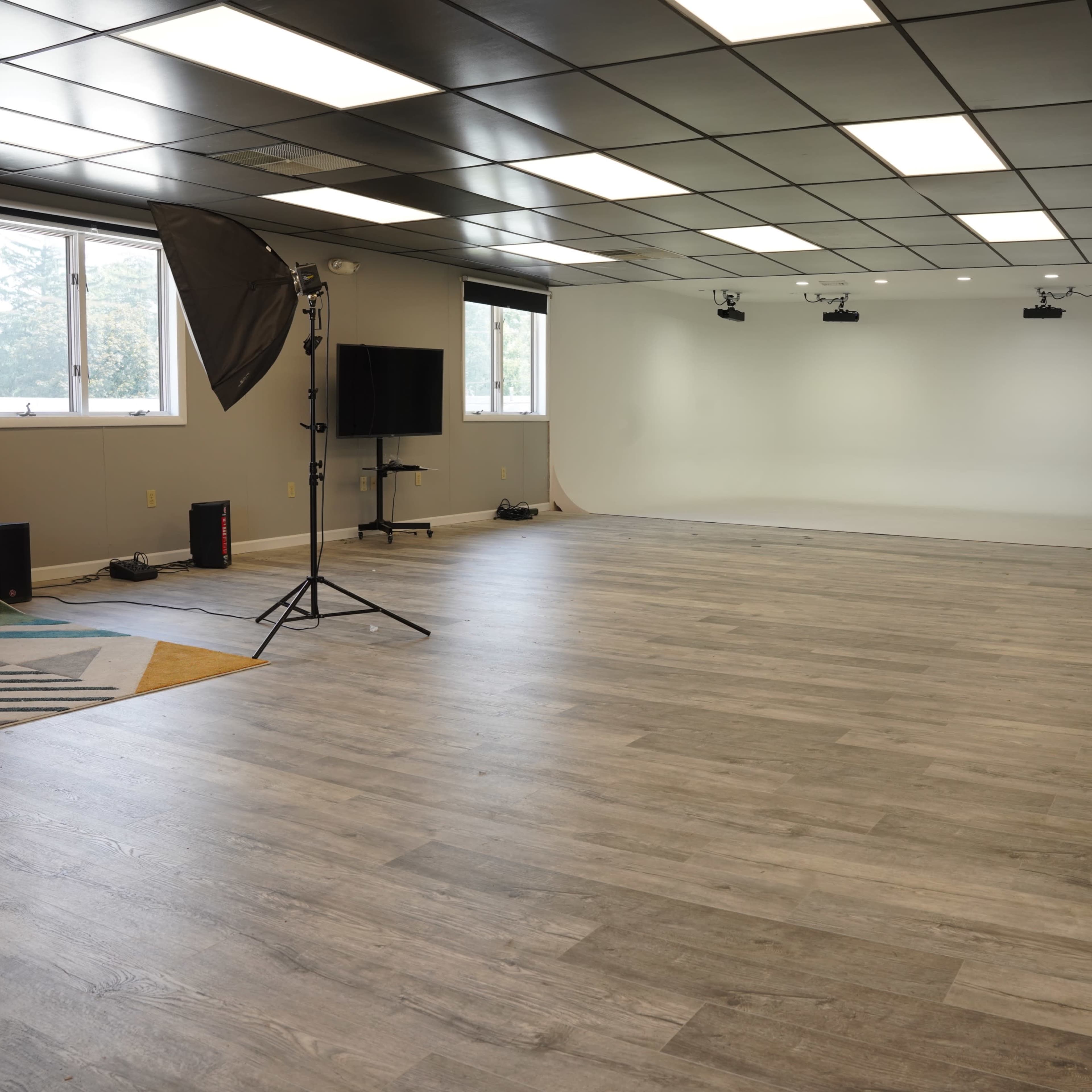 A spacious studio with wooden floors, soft lighting, and a backdrop area equipped for photography or videography.