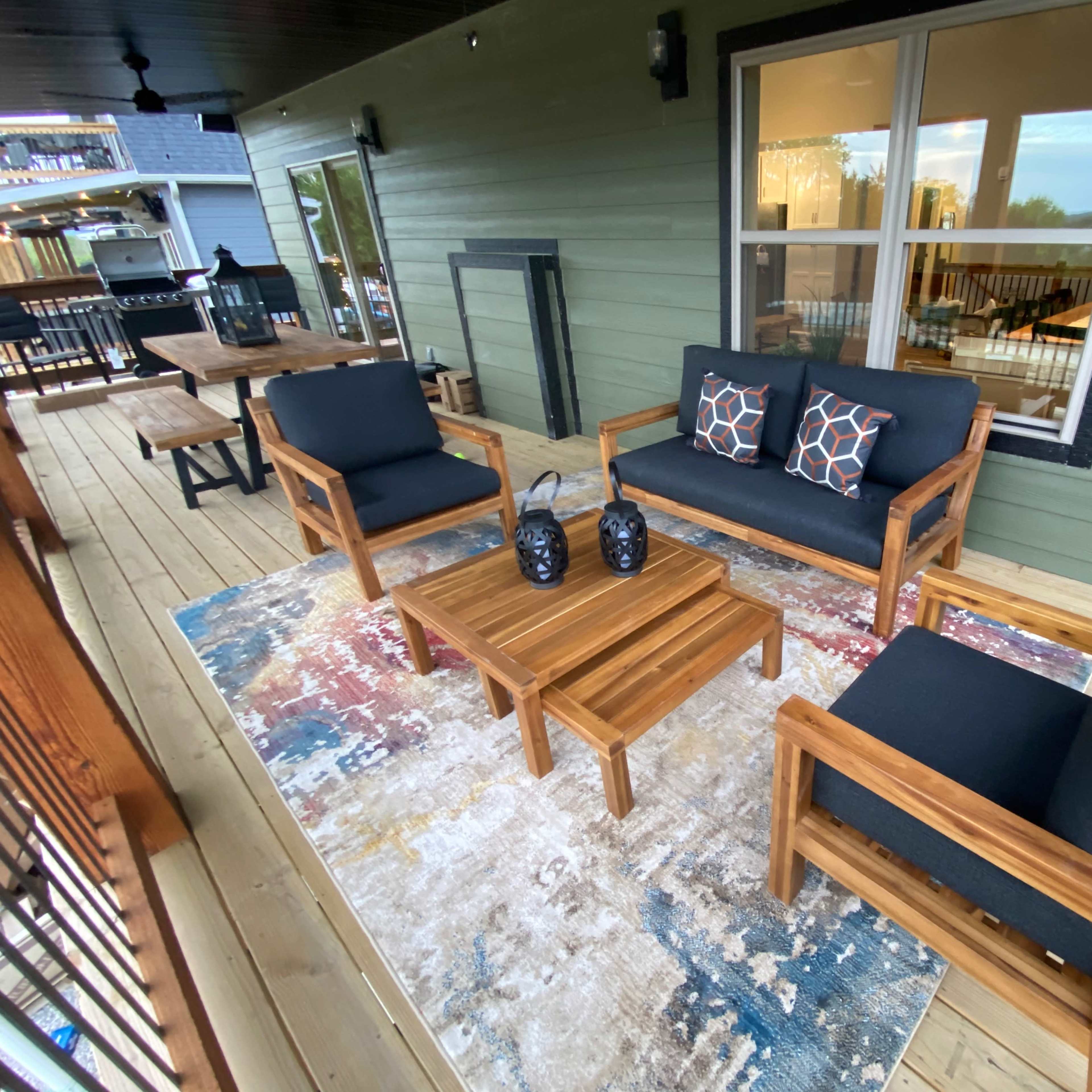 The patio features a seating arrangement with two armchairs and a loveseat around a coffee table on a rug.