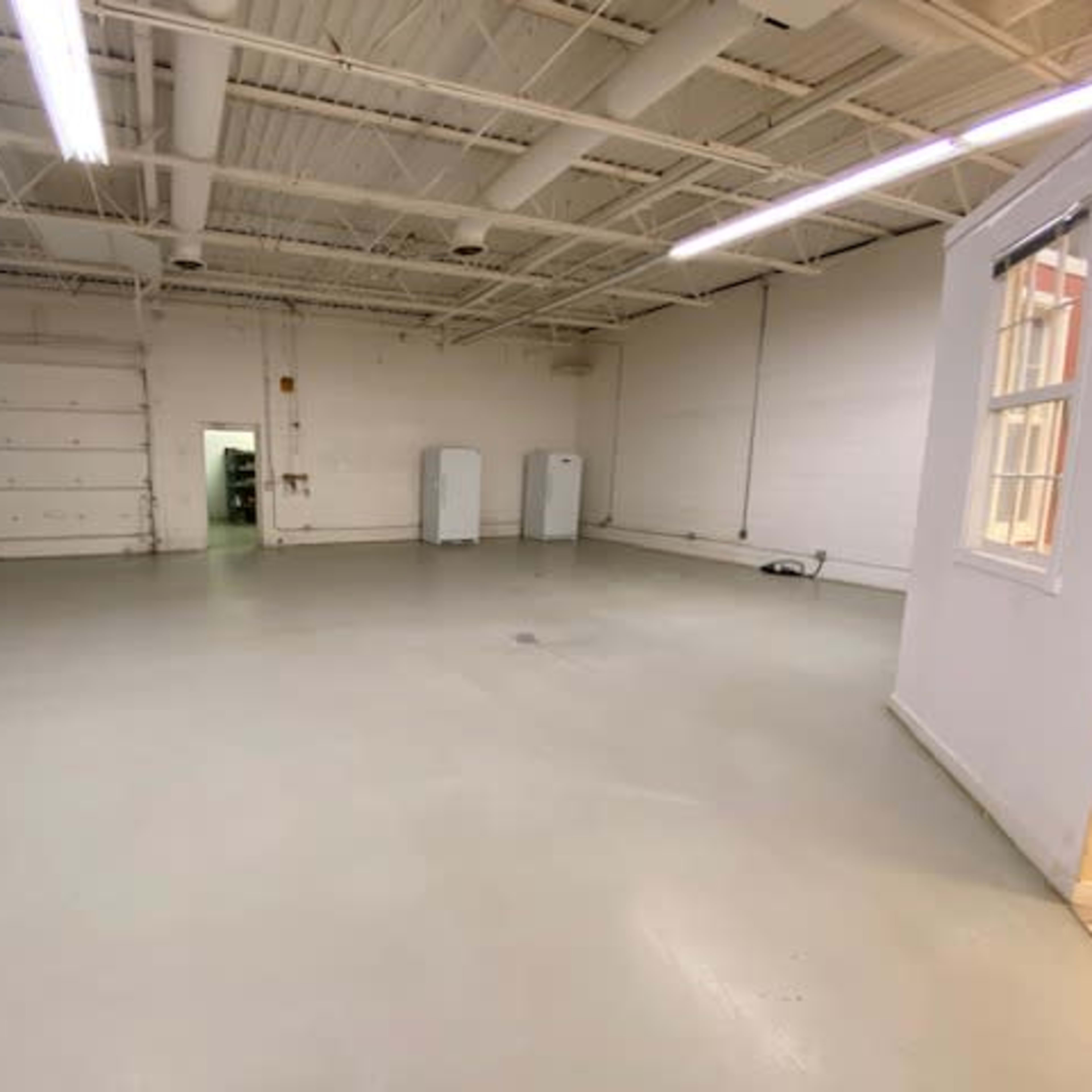 A large, empty commercial space with a smooth, light-colored floor and minimal fixtures.