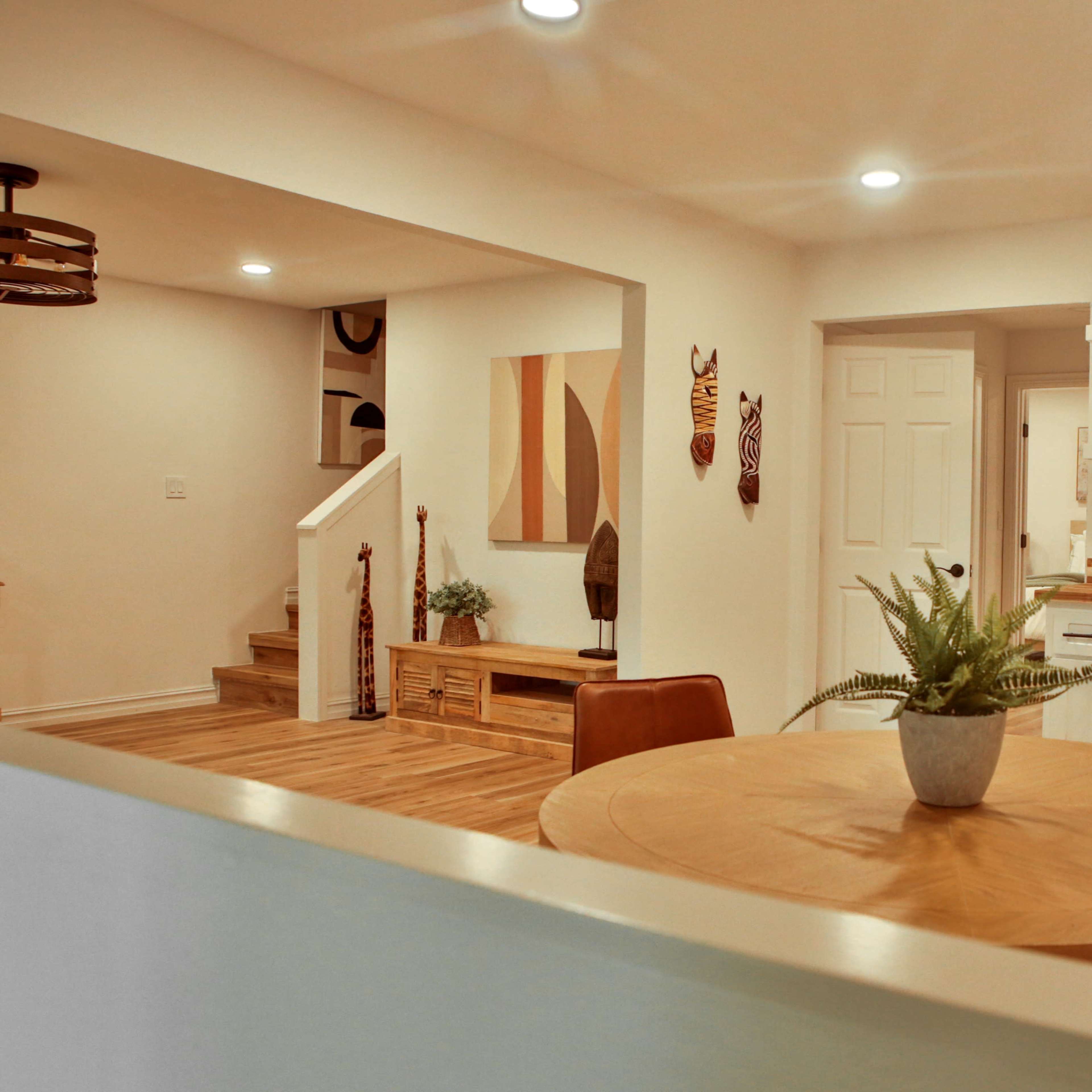 A modern kitchen and dining area featuring a round wooden table, white cabinetry, and decorative elements on the walls.