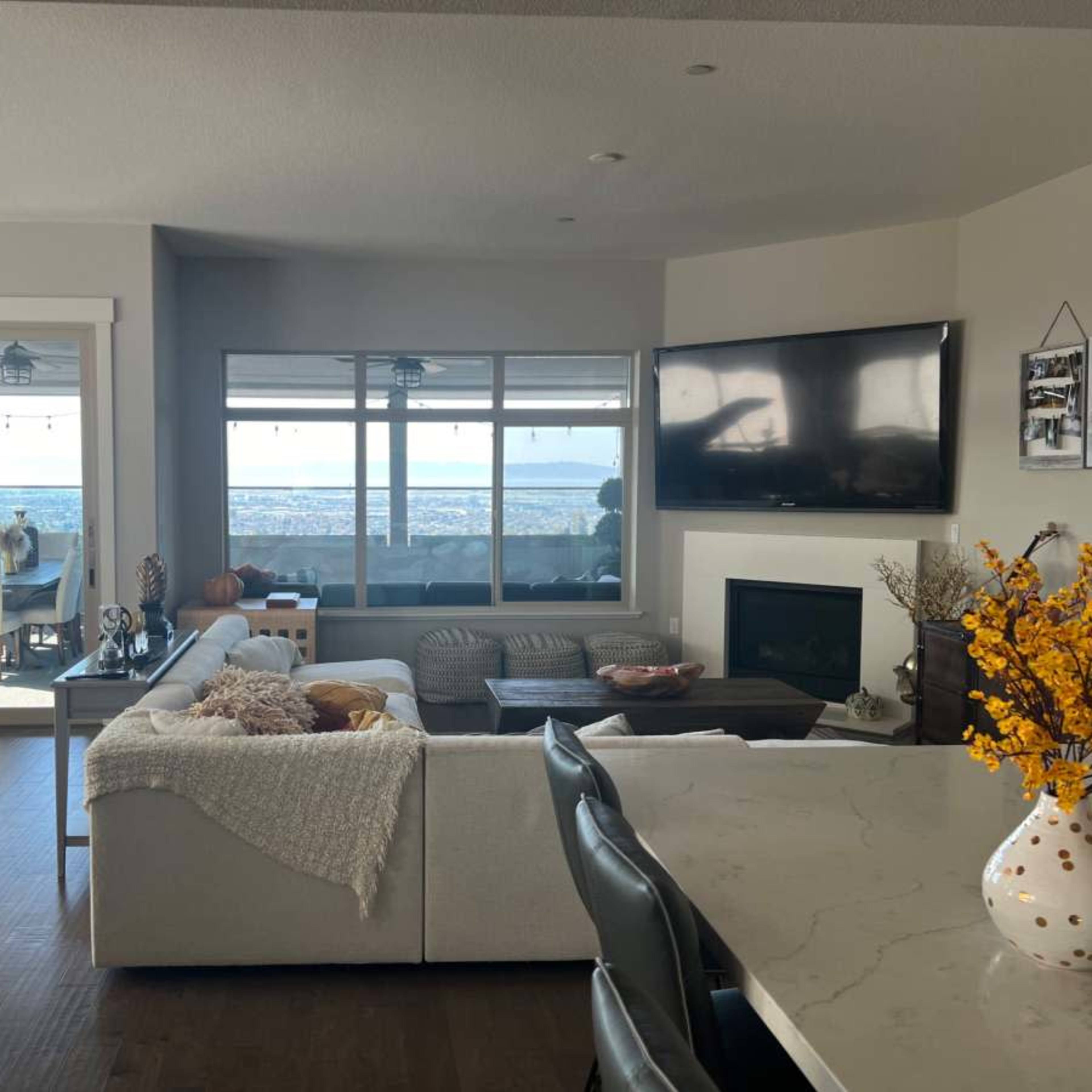 A modern open-concept living room and dining area with large windows offering a view of the outdoors.