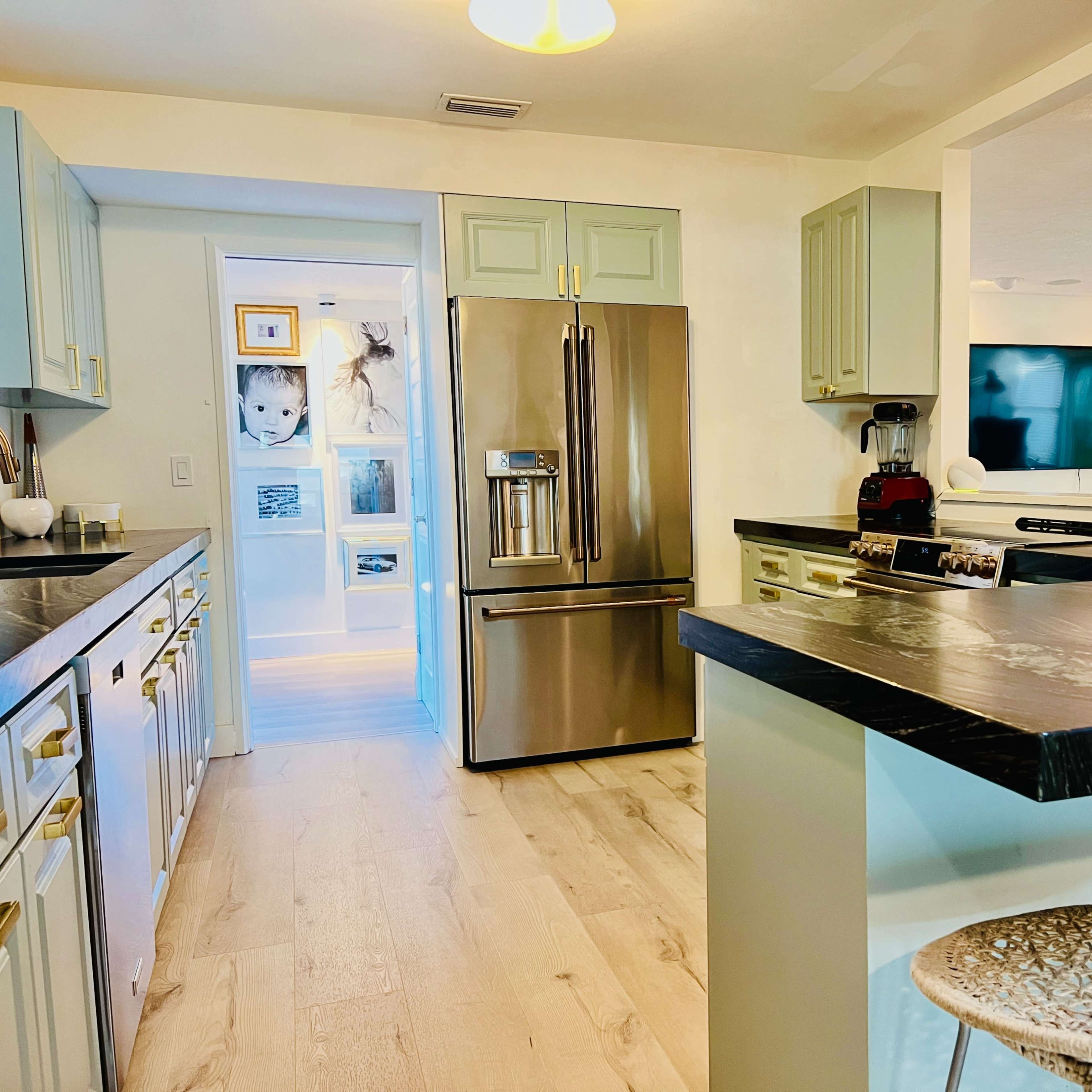 A modern kitchen features light cabinetry, stainless steel appliances, and an open layout leading to a living area.
