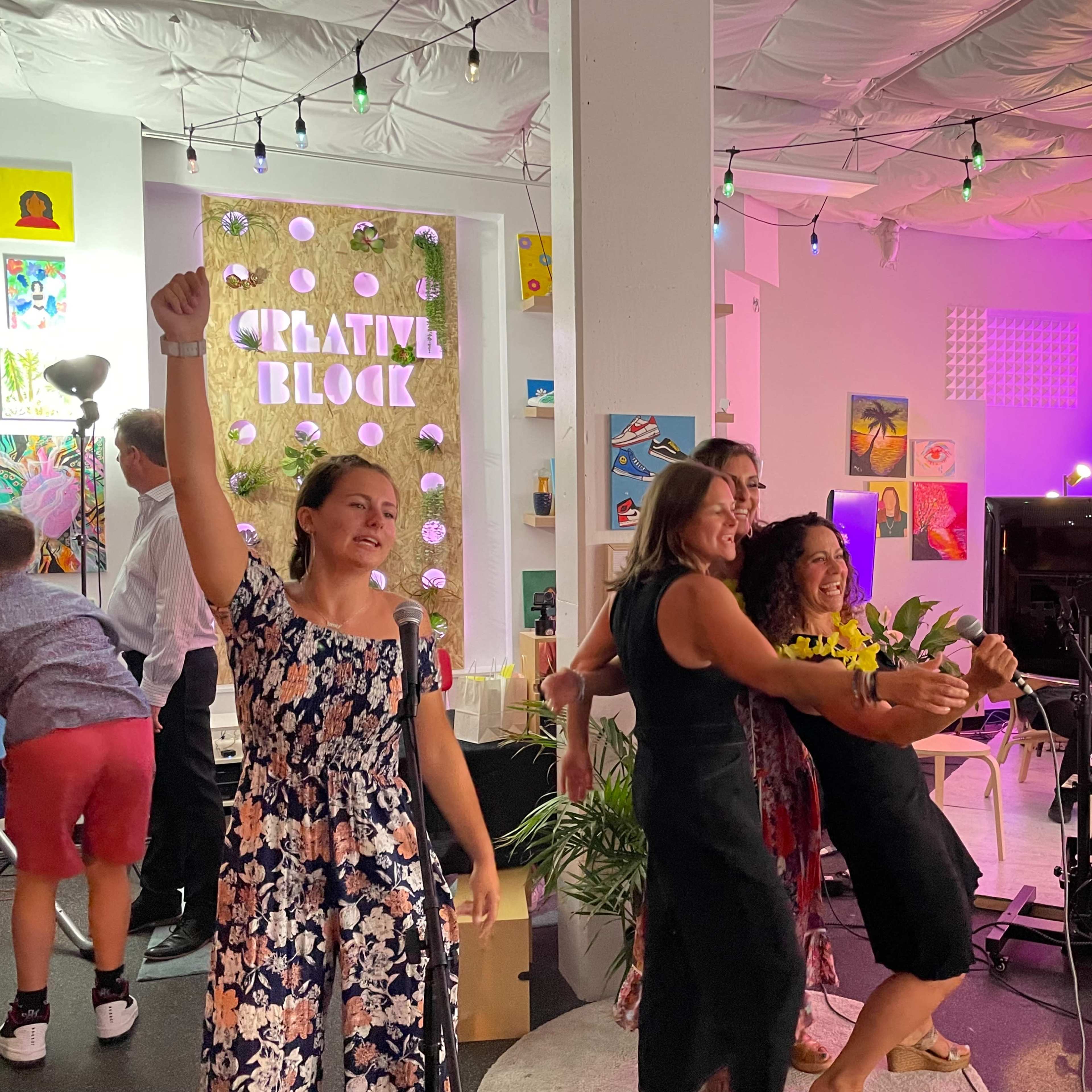 A group of people participates in a lively event inside a colorful, decorated space with various artworks on display.