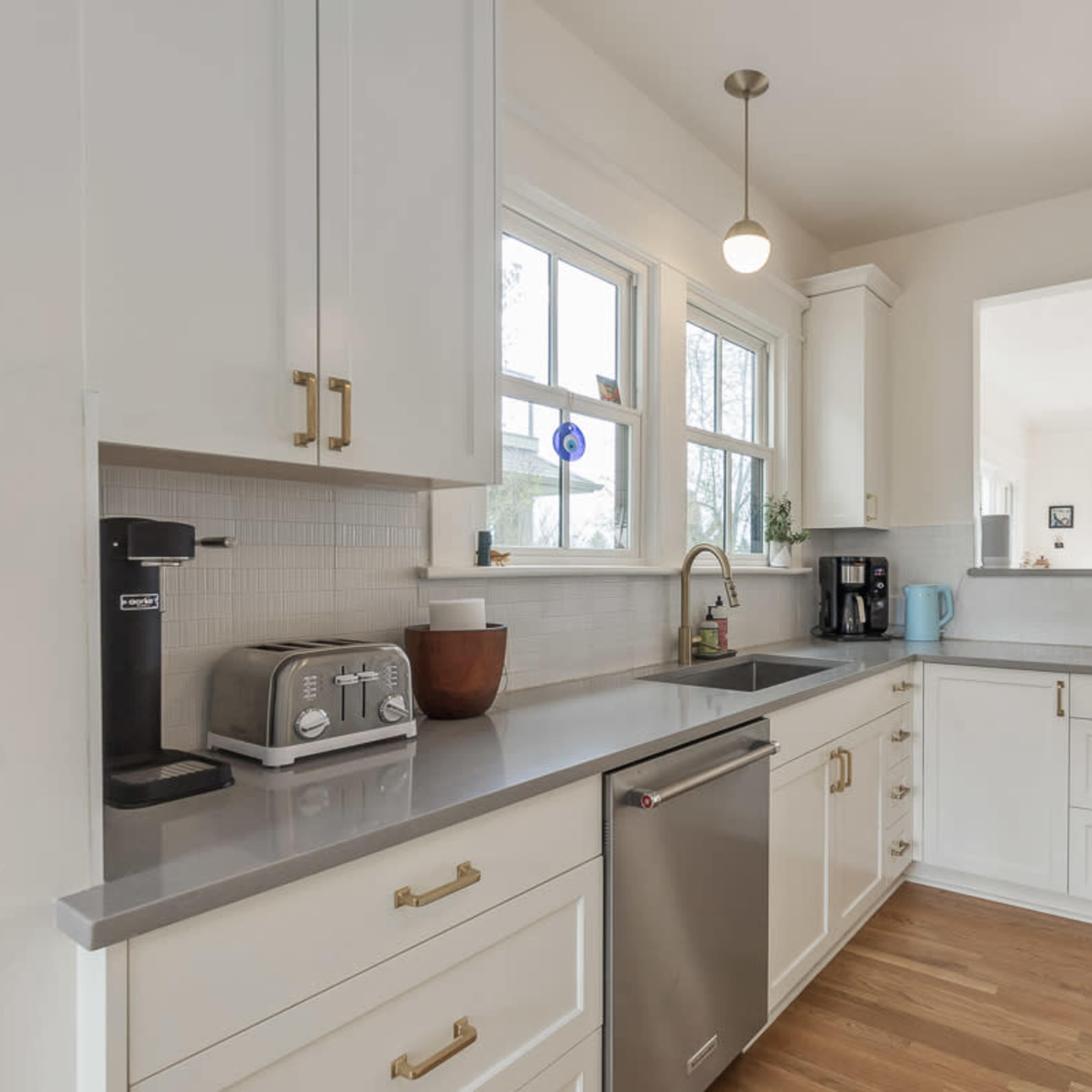 A modern kitchen with white cabinetry, quartz countertops, and appliances including a toaster and coffee maker.