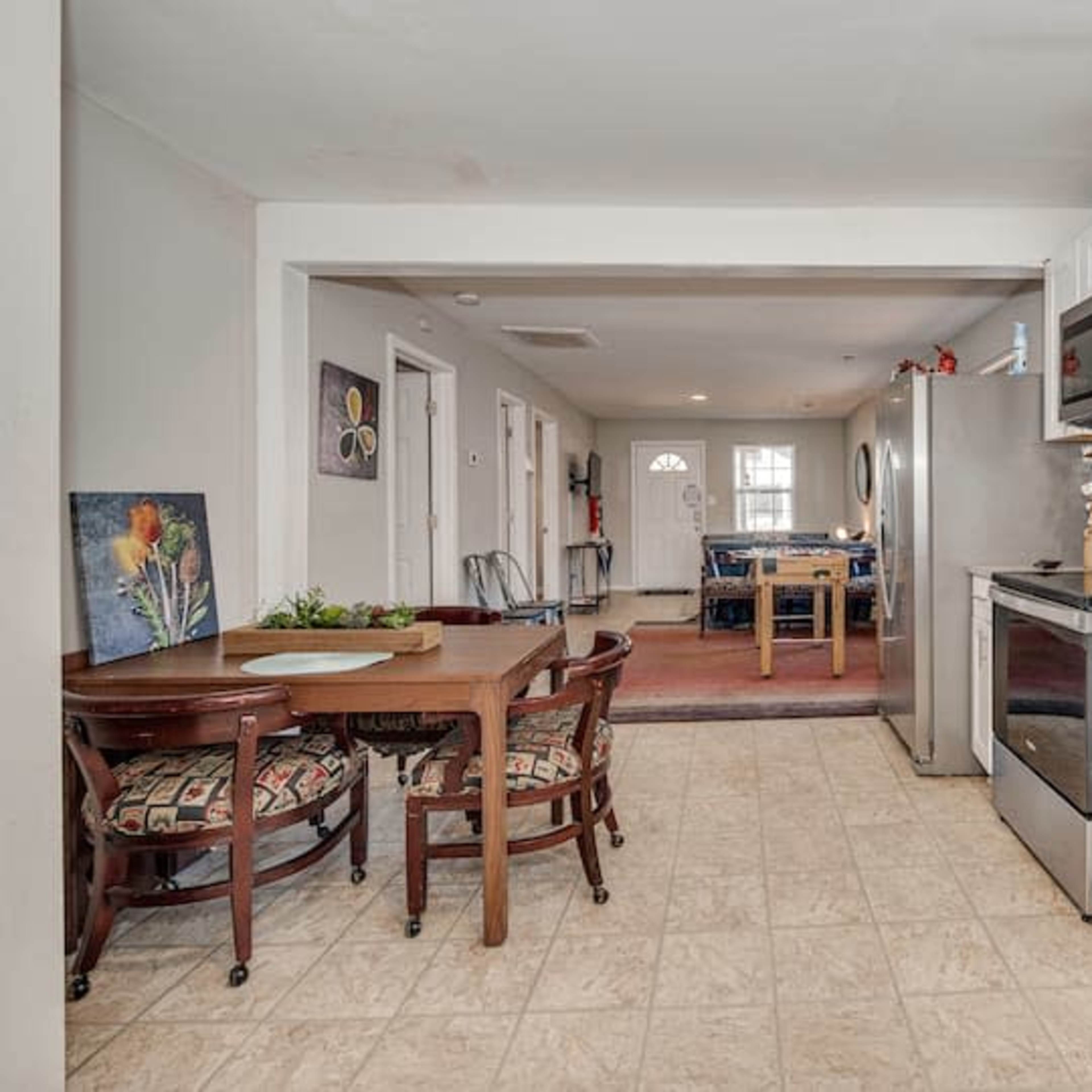 A spacious kitchen features white cabinetry, stainless steel appliances, and a small dining table adjacent to an open living area.