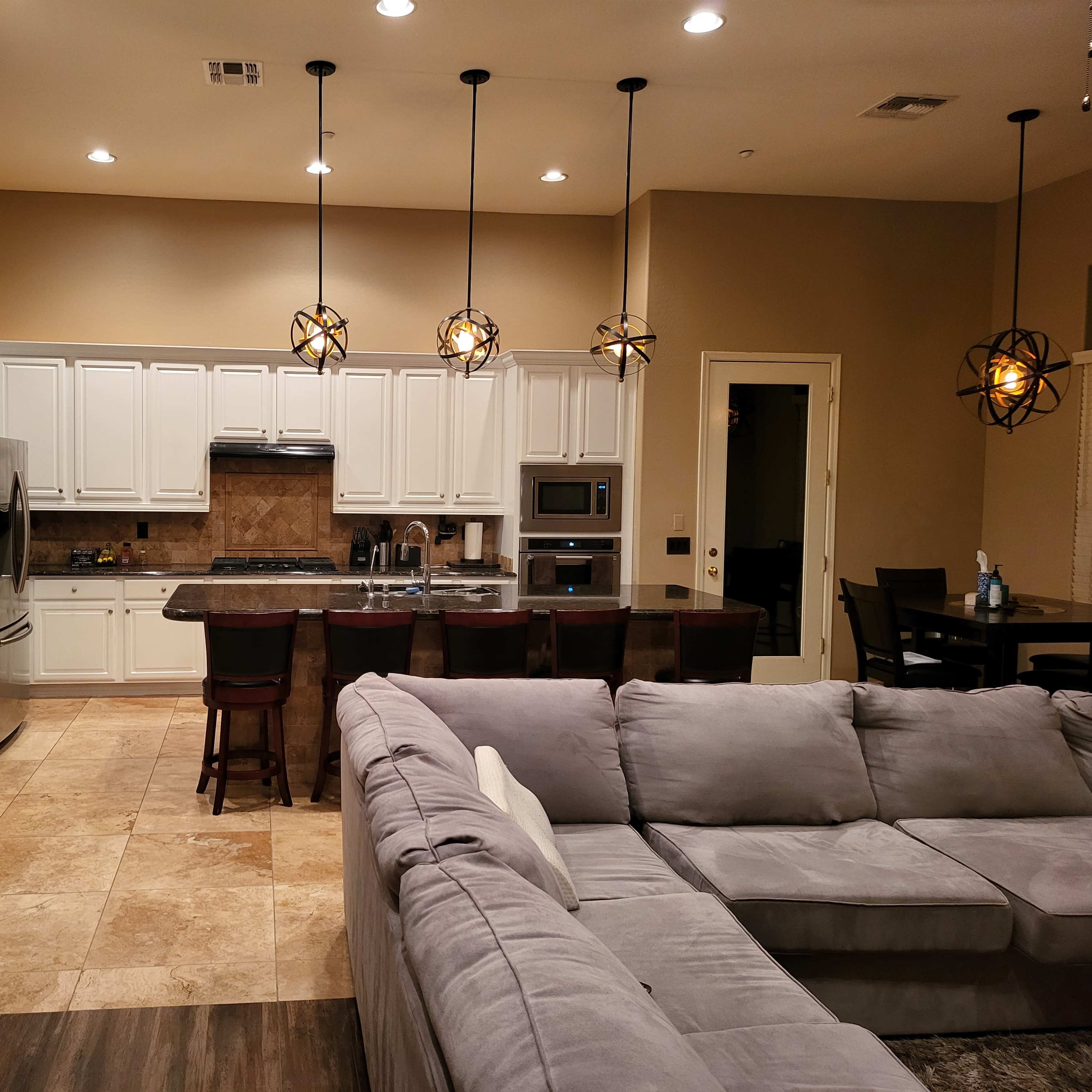 A modern kitchen with white cabinetry, stainless steel appliances, and a spacious living area featuring a large sectional sofa.