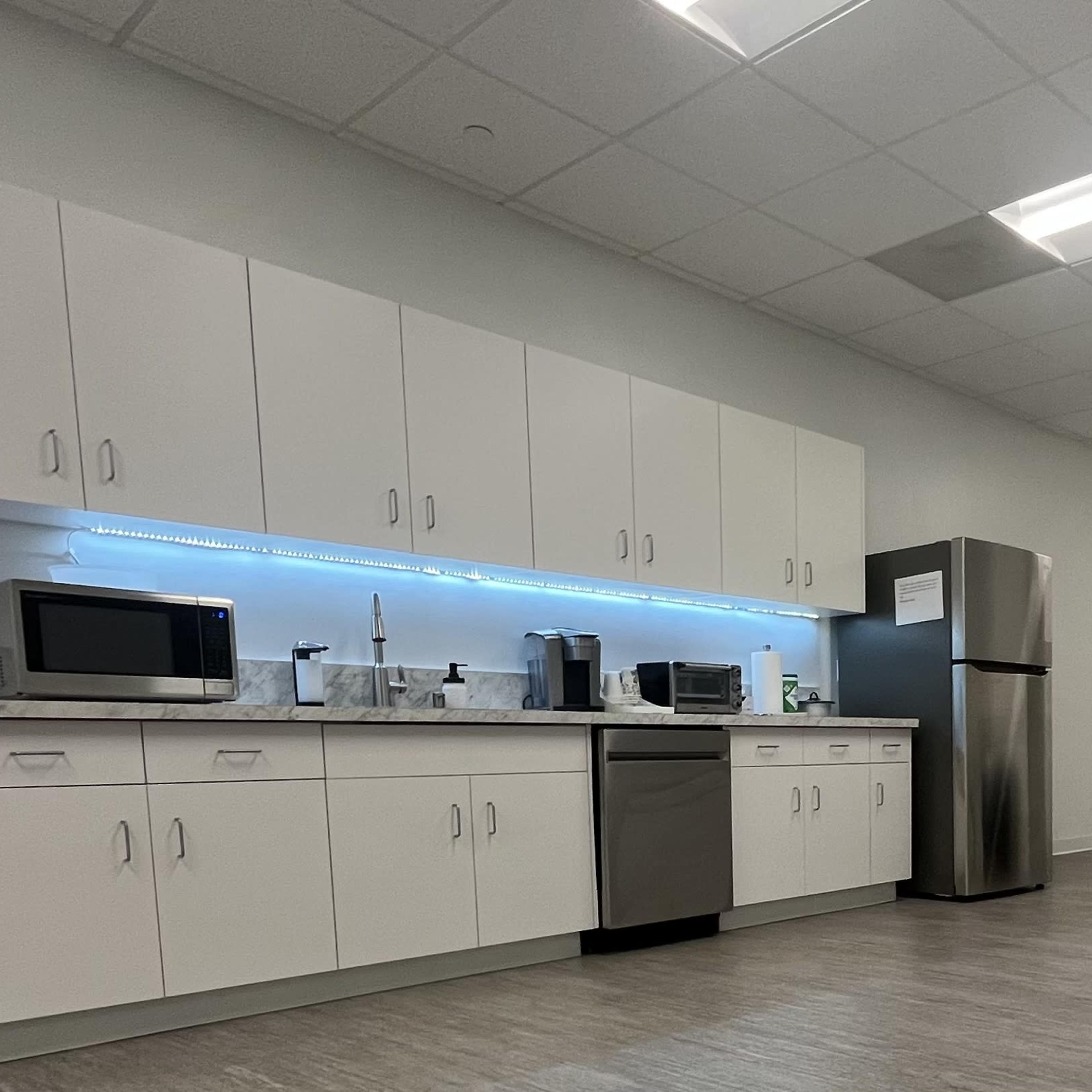 A modern kitchen area with white cabinetry, stainless steel appliances, and a countertop.