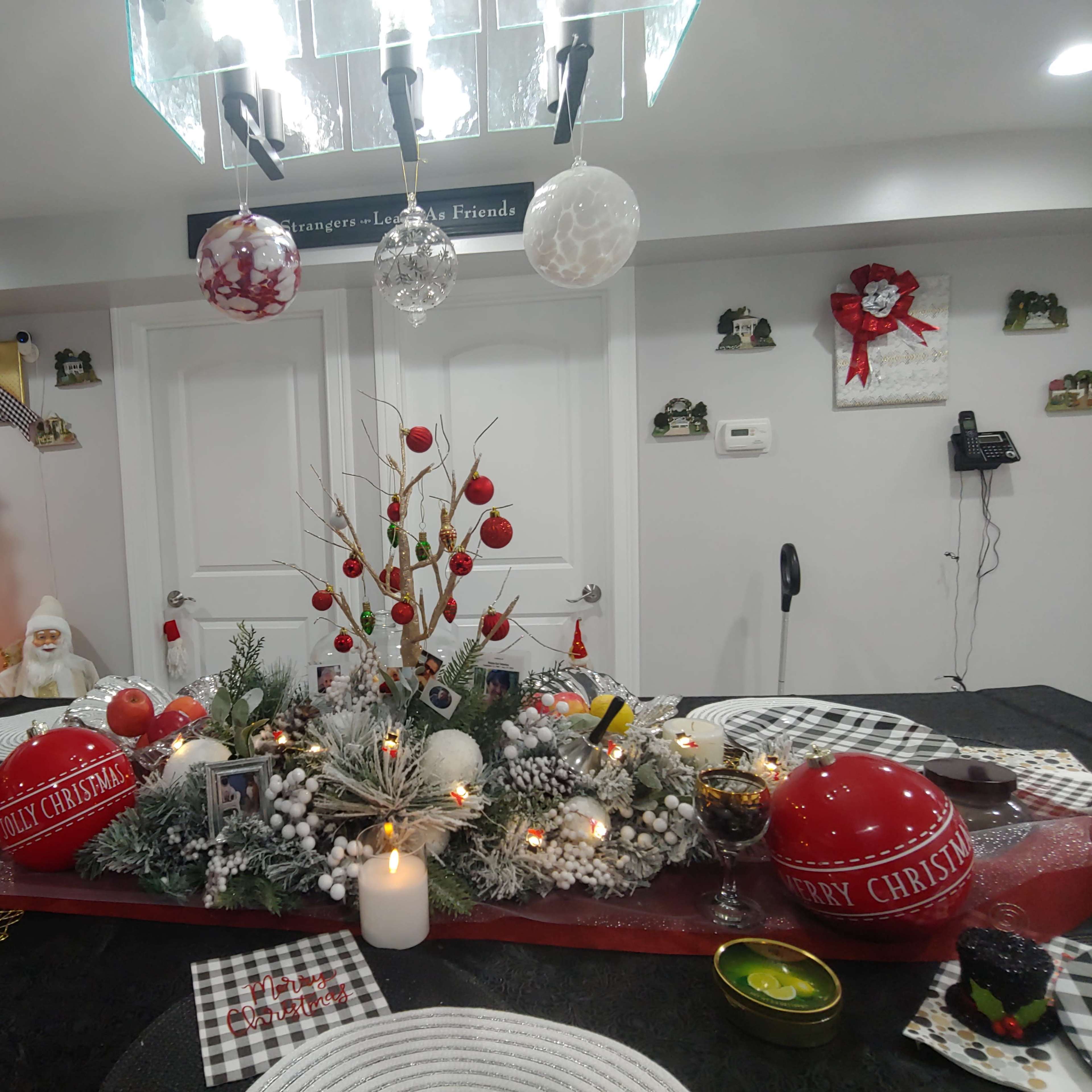 A decorated dining table with a festive centerpiece, surrounded by holiday decorations, a Christmas tree, and various ornaments.