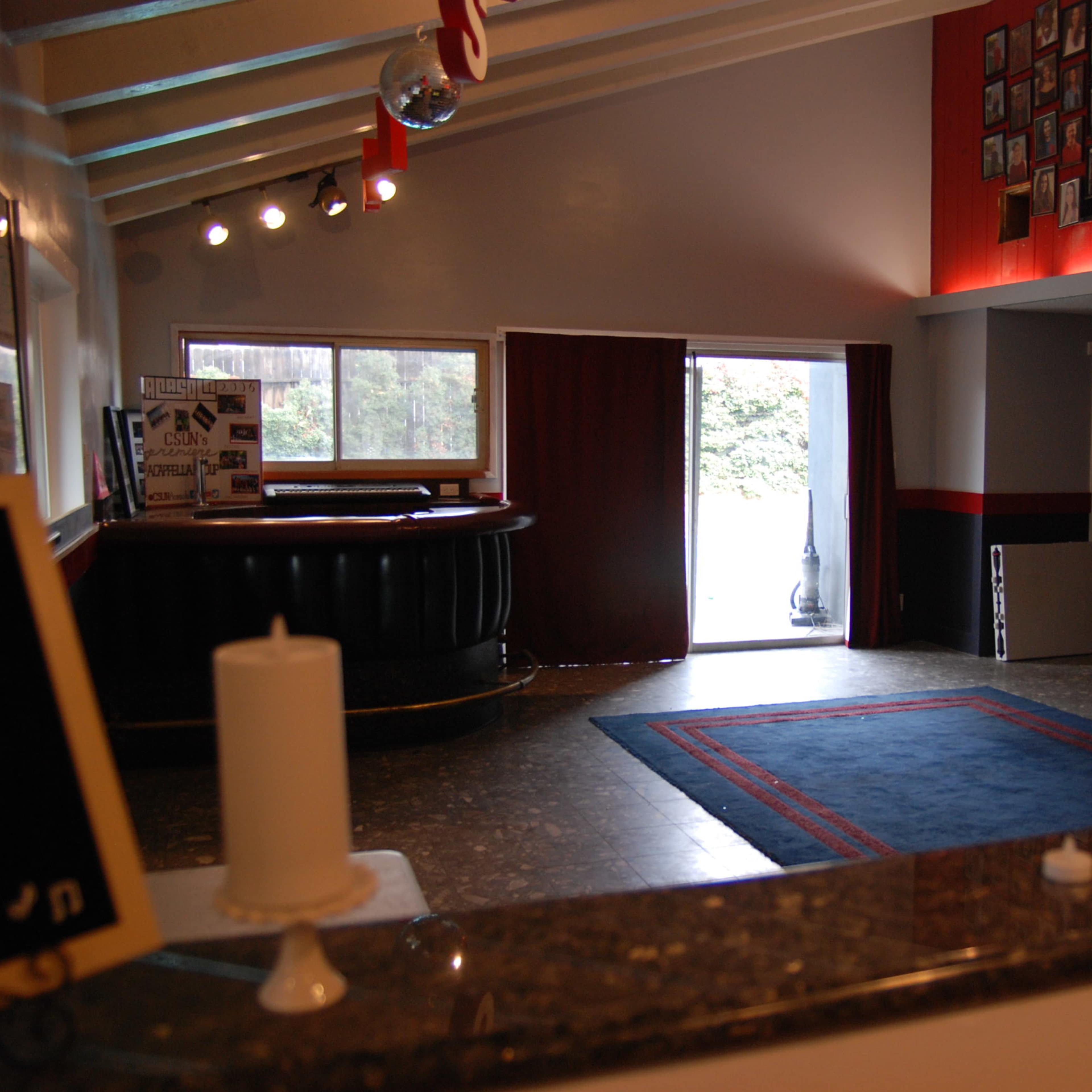 An interior room with a bar area, a patterned rug on the floor, and a large wall displaying numerous framed photos.