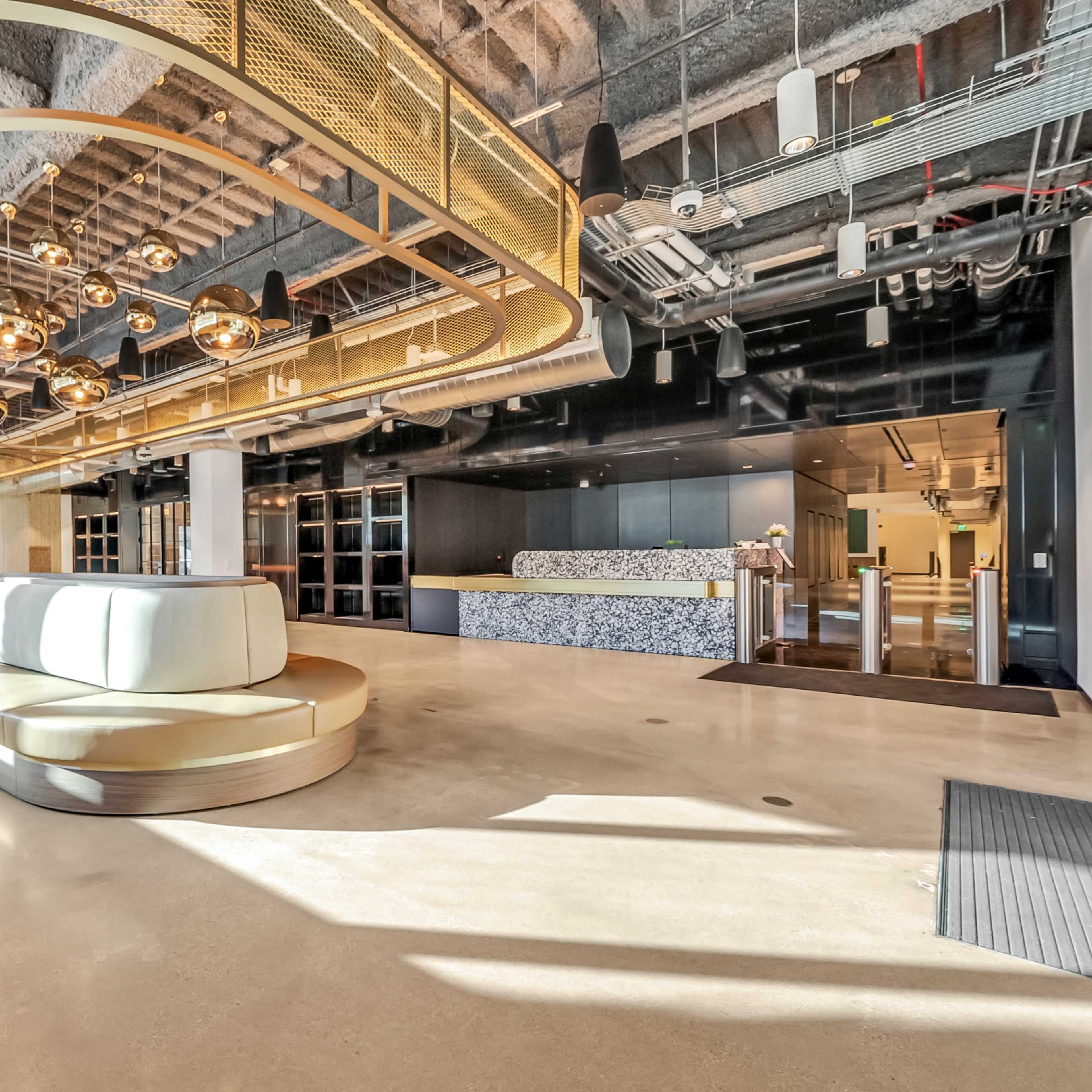 A modern lobby area featuring a curved seating arrangement, pendant lighting, and a reception desk.