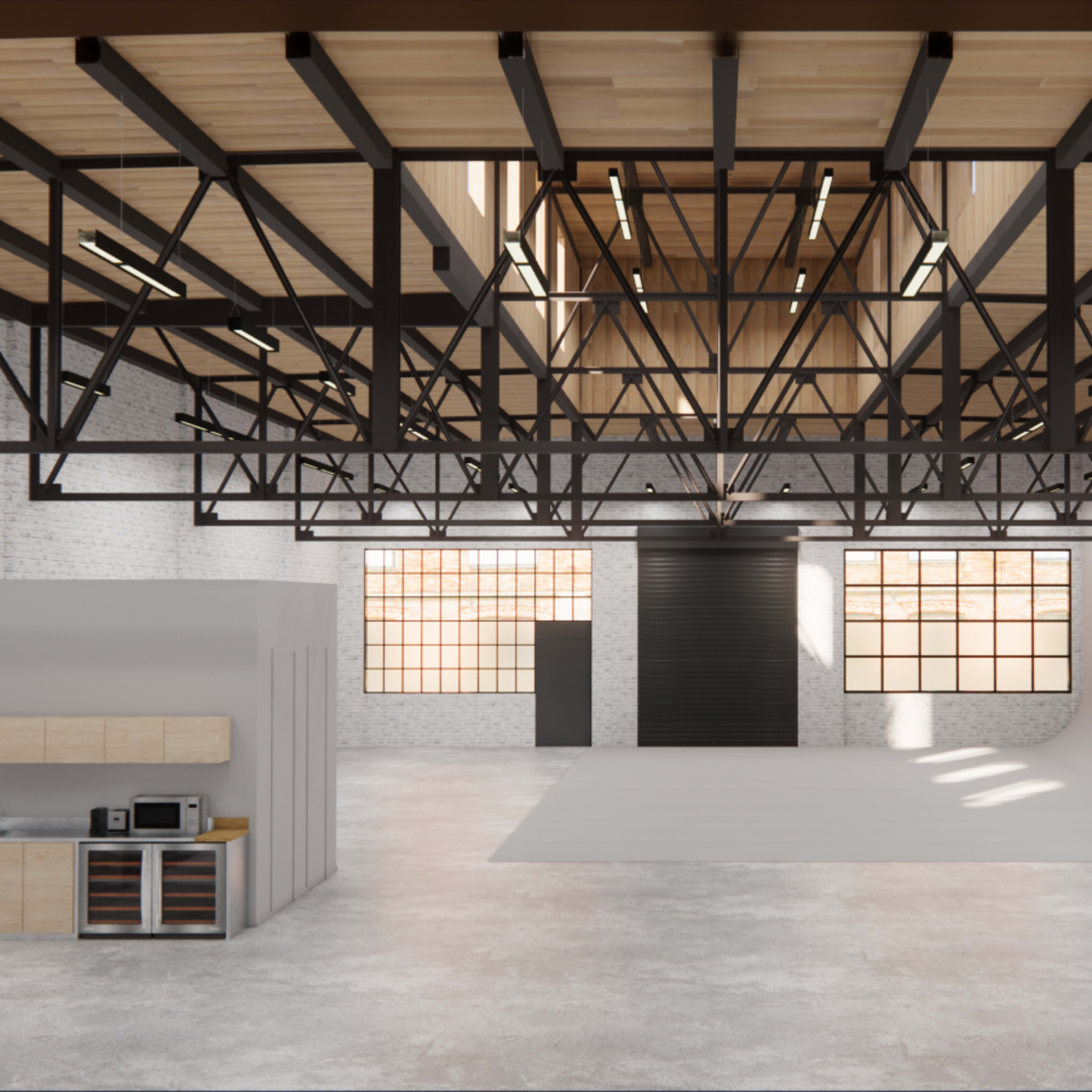 A spacious industrial studio with high ceilings, exposed brick walls, and large windows, featuring a kitchen area and a seamless backdrop for photography.
