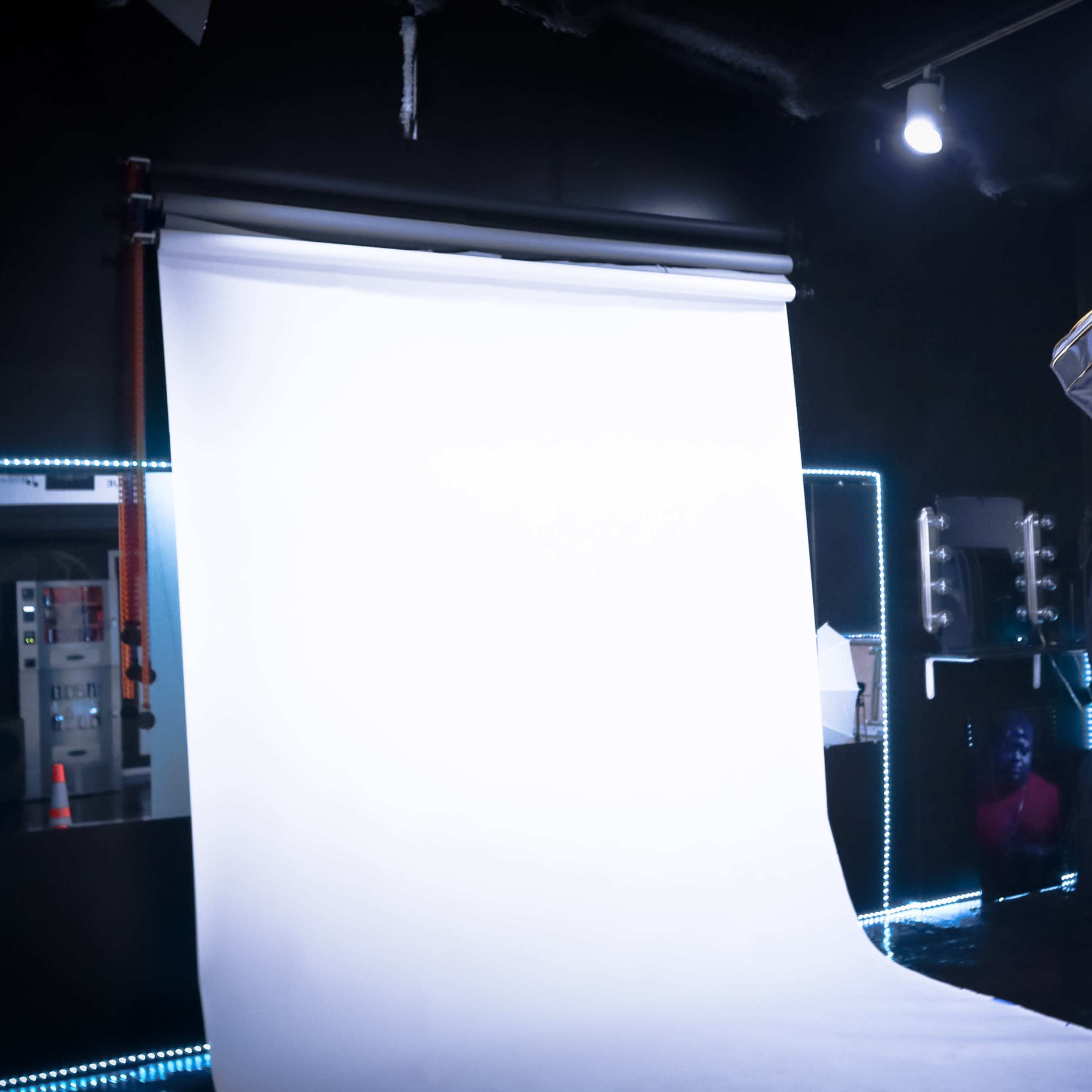 A photography studio is set up with a large white backdrop, studio lights, and various lighting equipment.