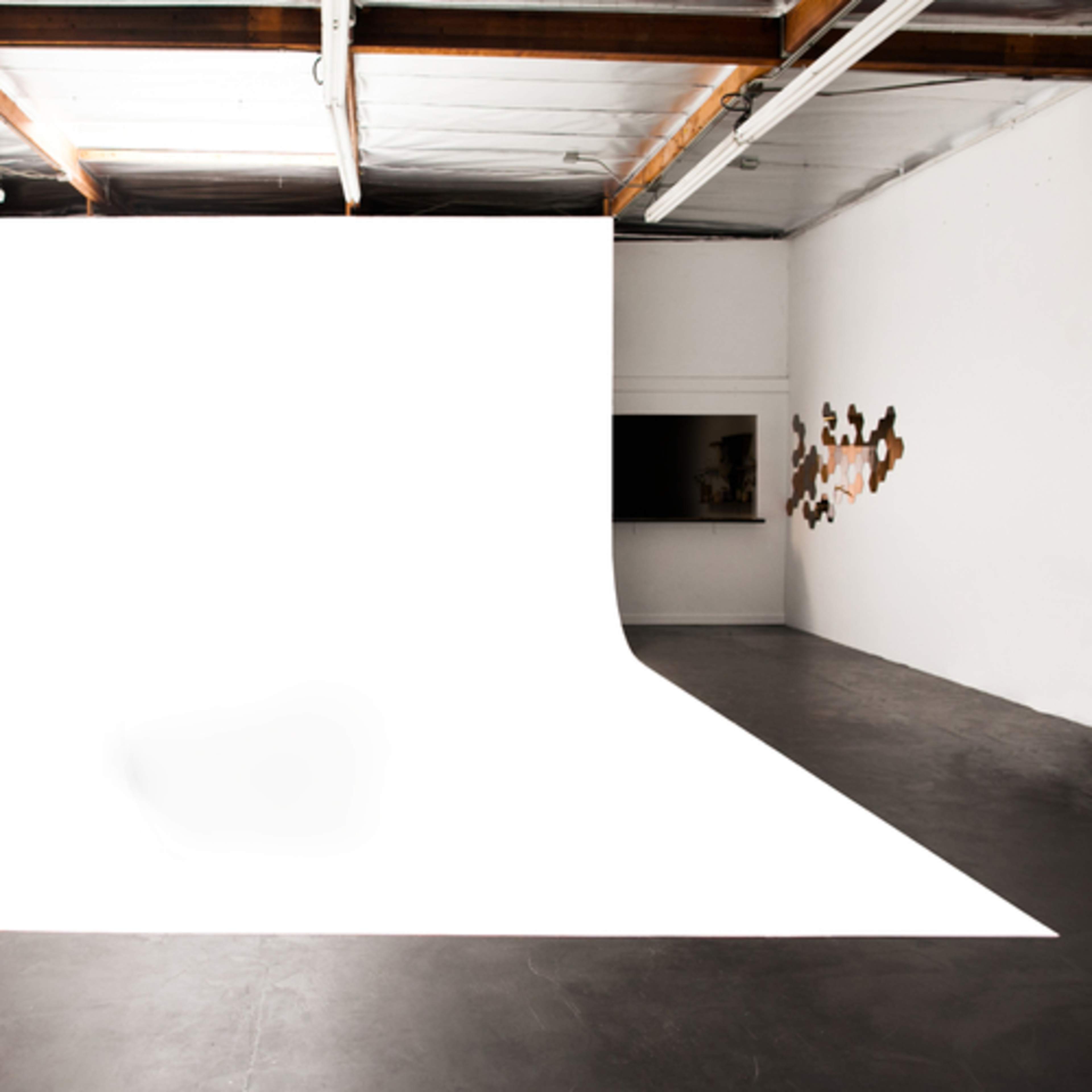 A spacious studio with a seamless white backdrop and polished concrete flooring.
