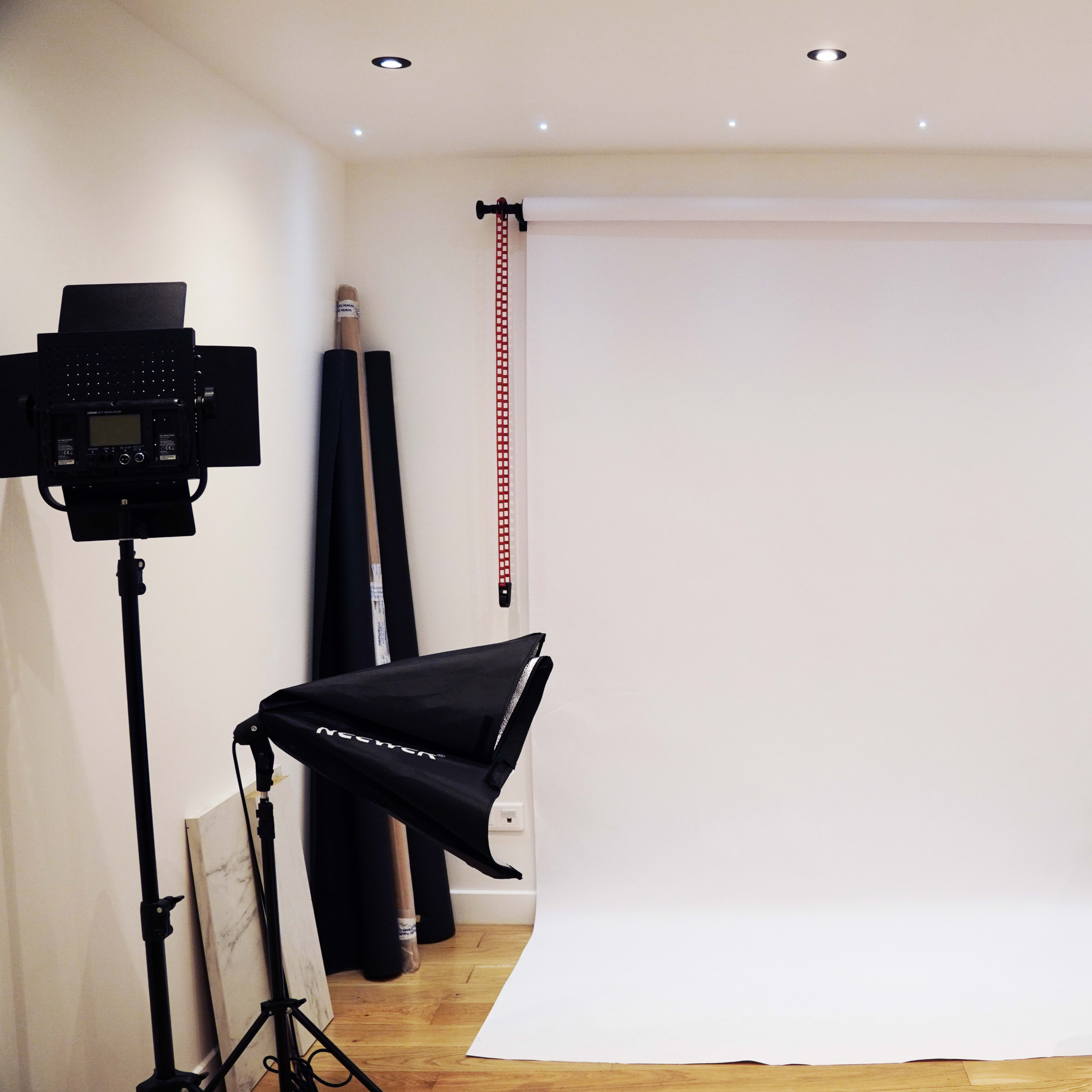 A photography studio setup with a white backdrop and two lighting stands on either side.