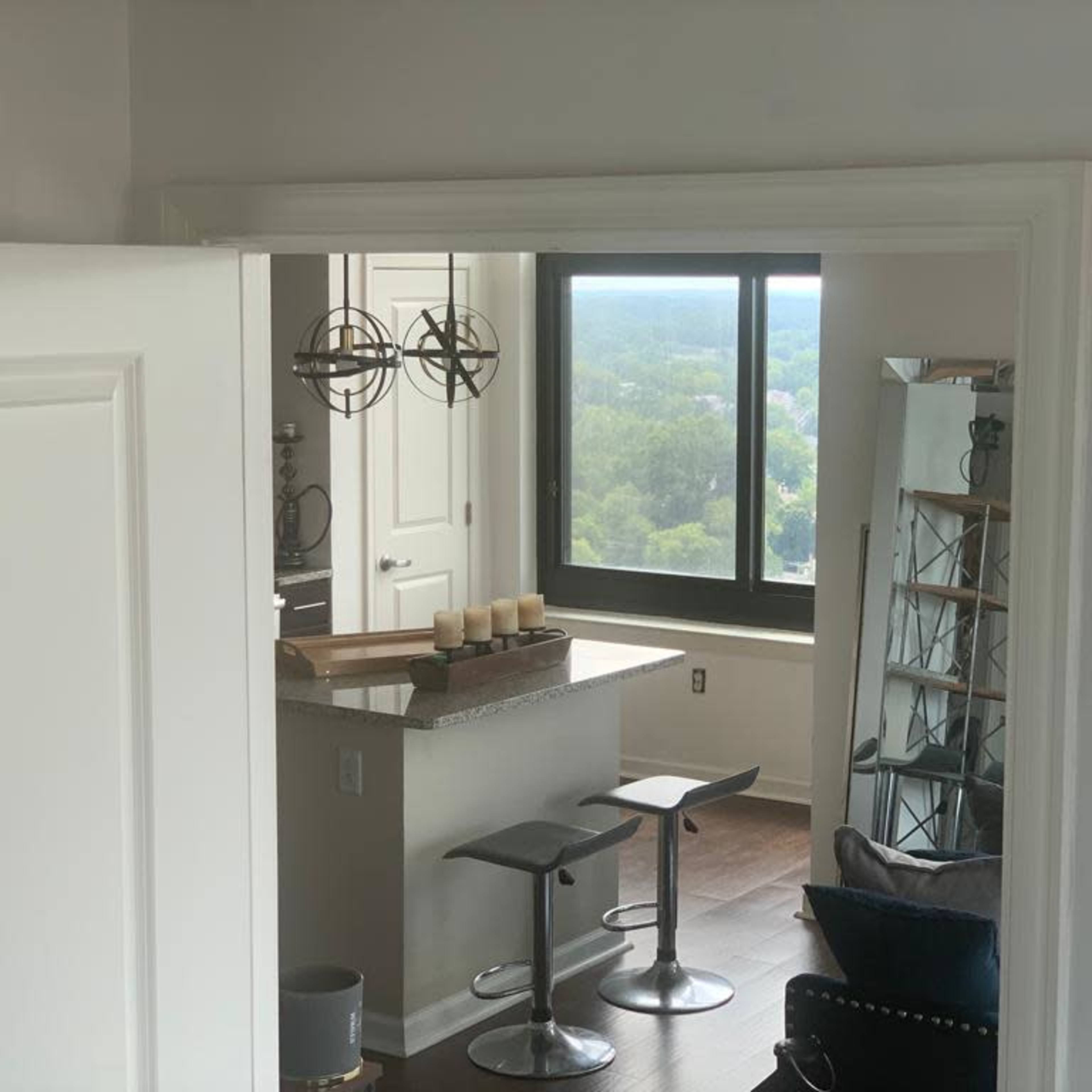 A modern interior view of an open-concept living space with a kitchen and seating area visible through a doorway.